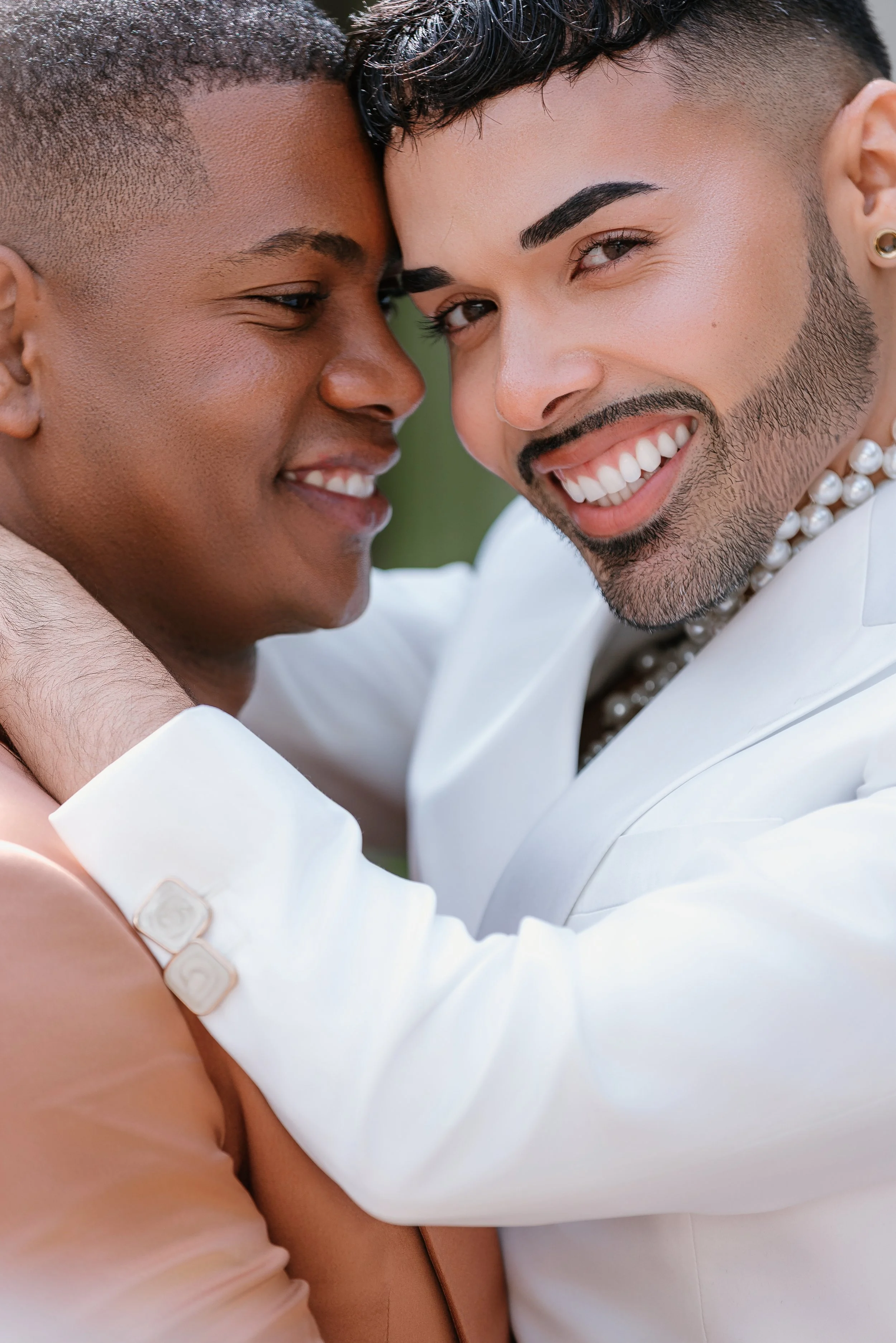 Two people smiling close together, showing affection in an outdoor setting.