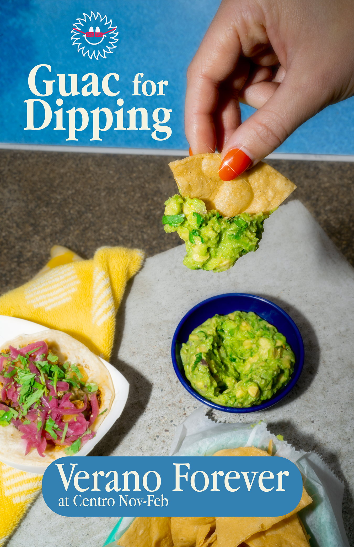 A hand with orange nail polish dipping a tortilla chip into a bowl of guacamole, with a box of Guac for Dipping and a taco with pink pickled onions and cilantro visible in the background.