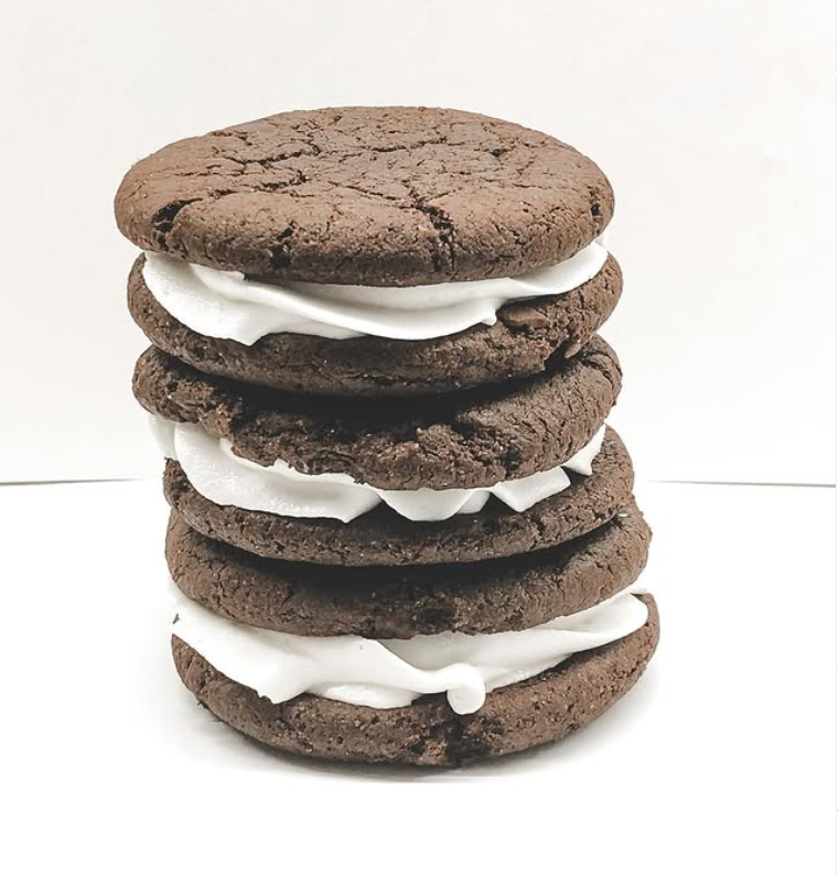 A stack of five chocolate cookies with white cream filling in between each cookie.