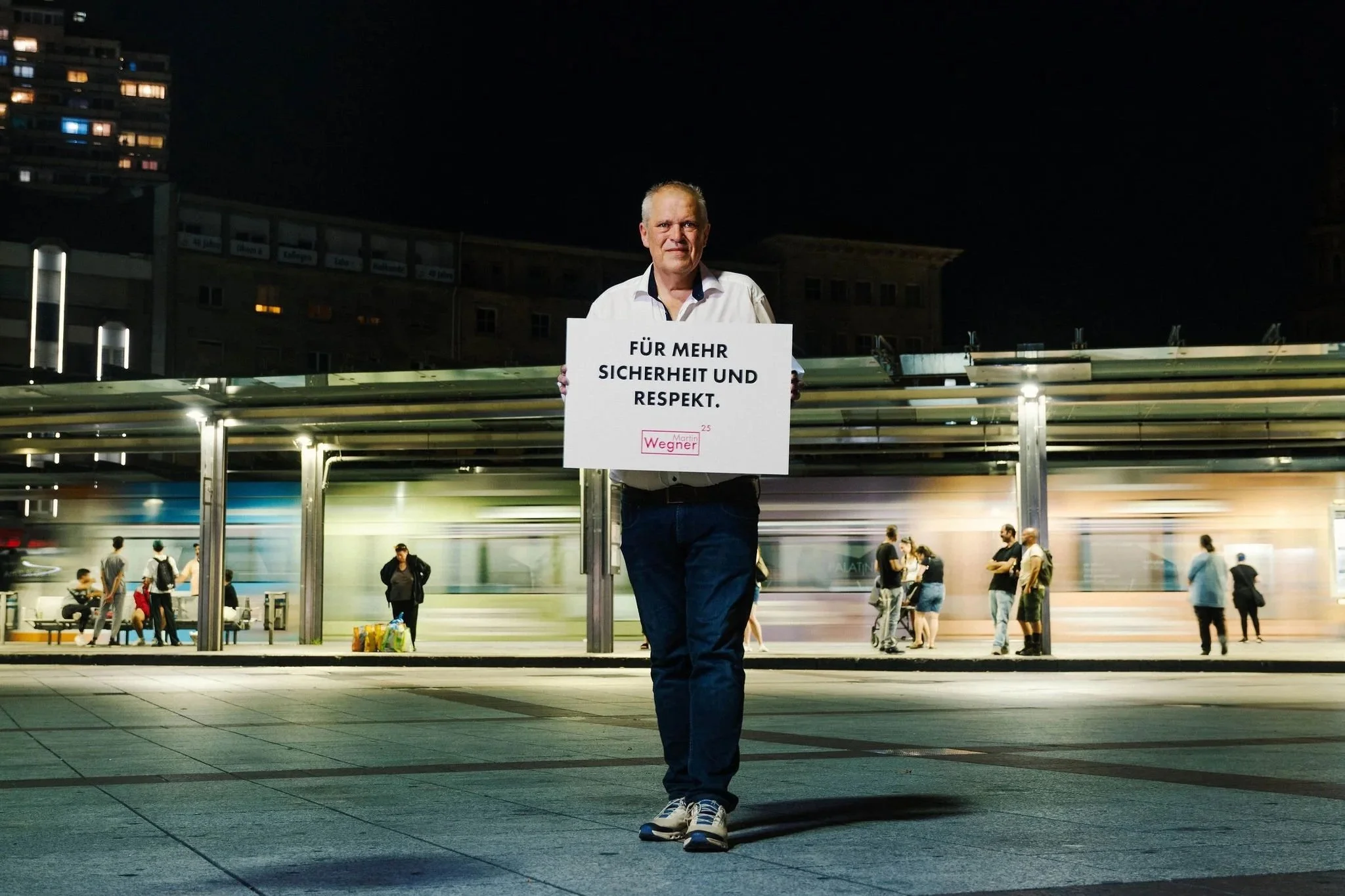 Martin Wegner Oberbürgermeisterkandidat für  Ludwigshafen  steht nachts an einer Bushaltestelle, hält ein Schild mit der Aufschrift »Für mehr Sicherheit und Respekt«