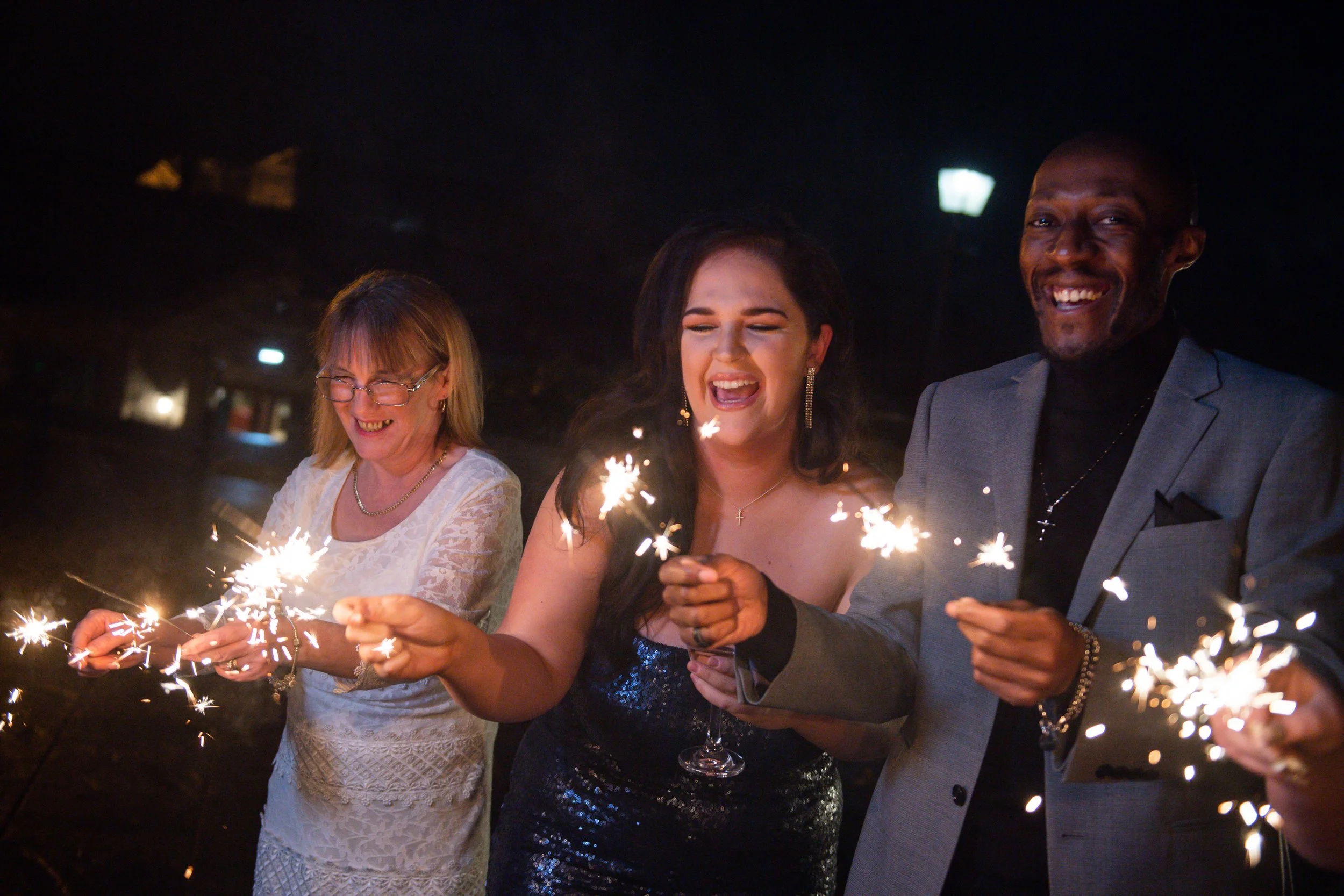 People celebrating with sparklers at night, smiling and enjoying the moment.