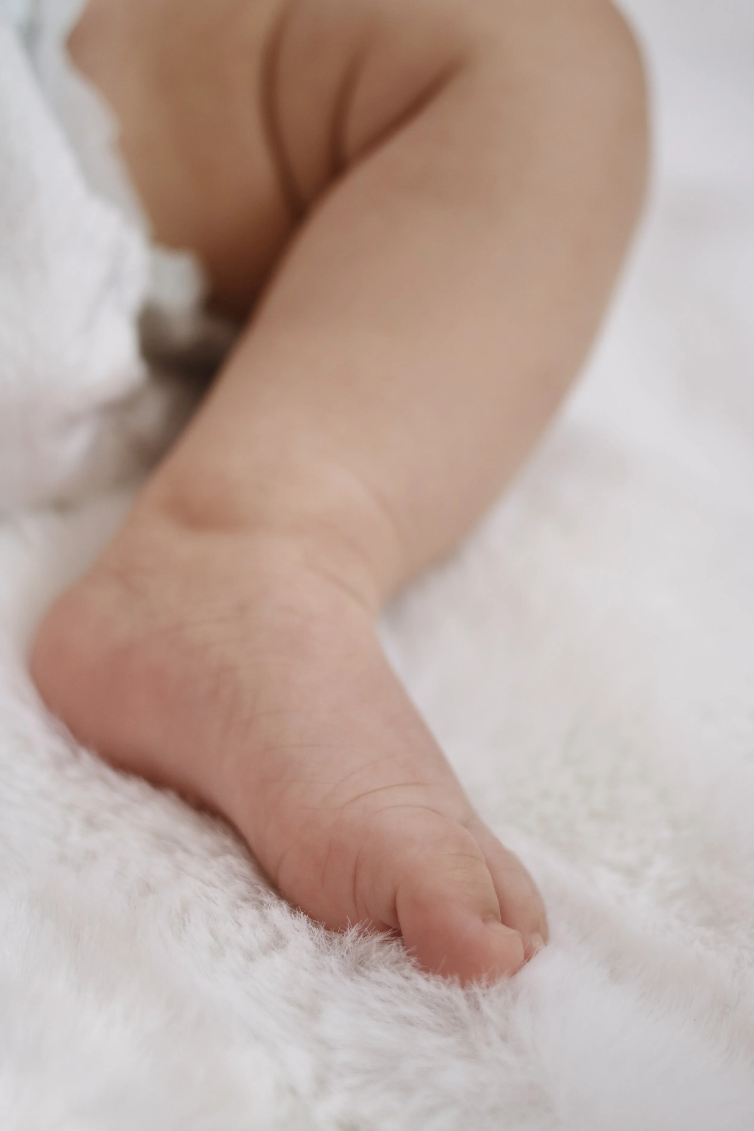 Close-up of a baby's foot resting on a white, fluffy surface.