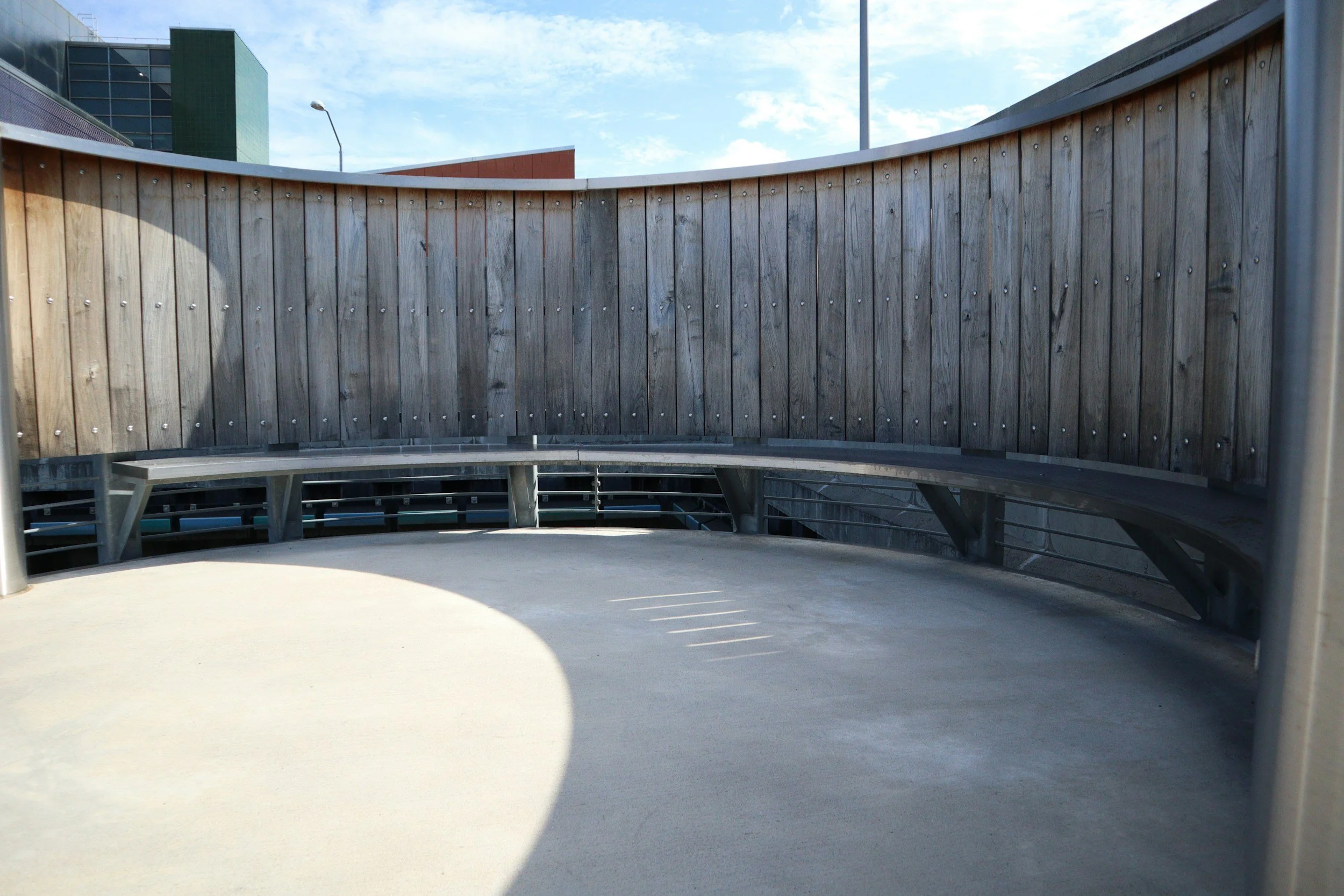 Leerer Balkon mit Holzwand und Blick auf den Himmel und moderne Gebäude im Hintergrund.