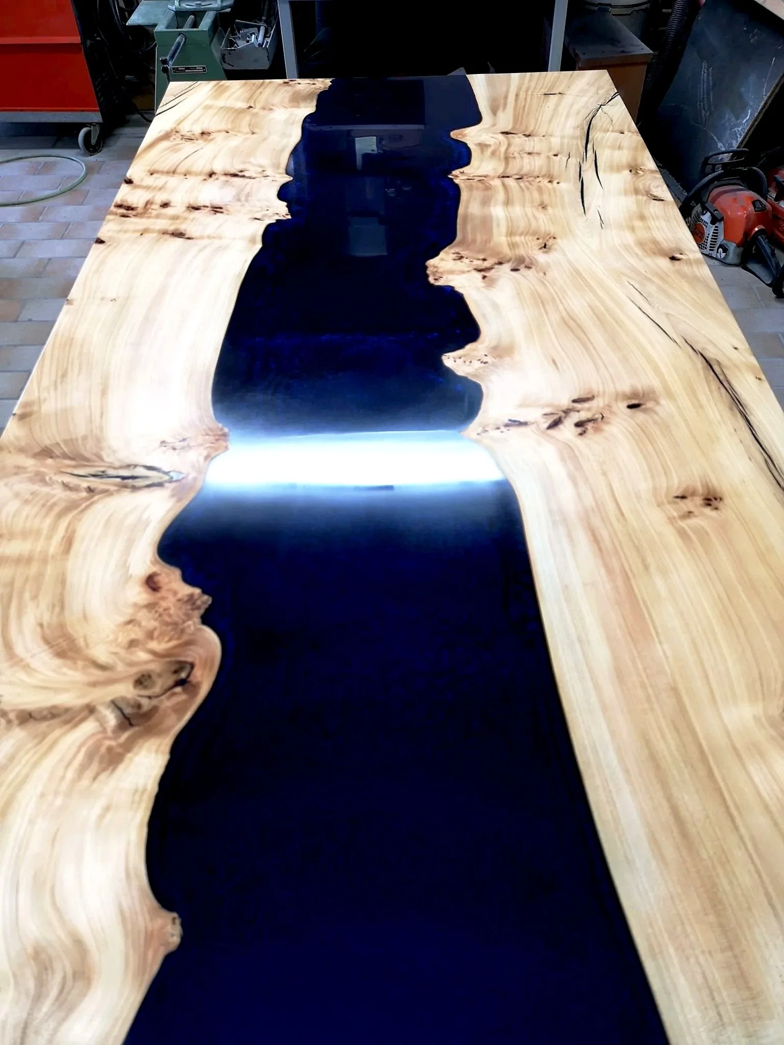 Holztisch mit eingegossenem blauen Epoxidharz in einer Werkstatt.