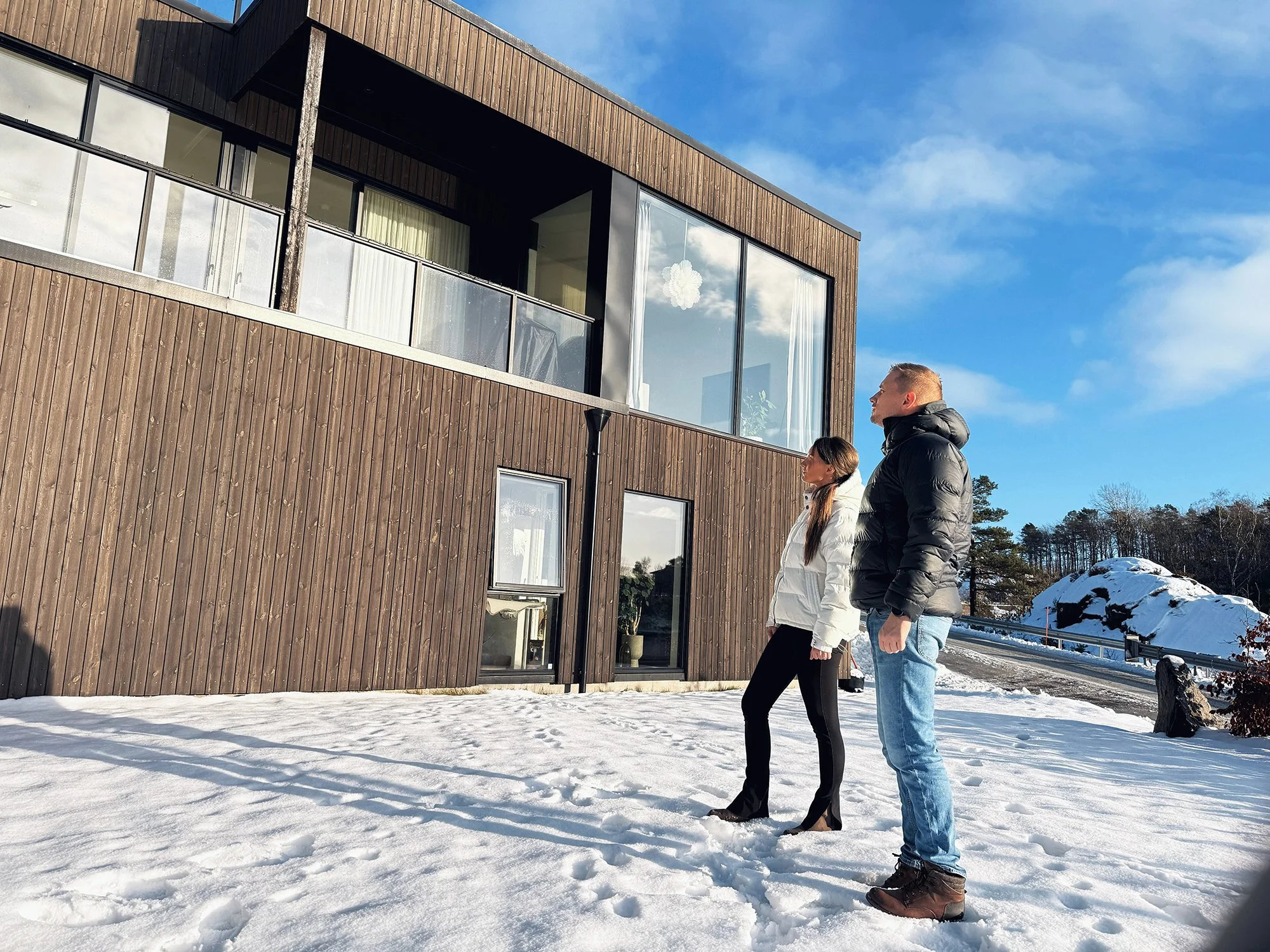 Arkitekter på befaring i snødekt terreng utenfor moderne bygg med glassfasade