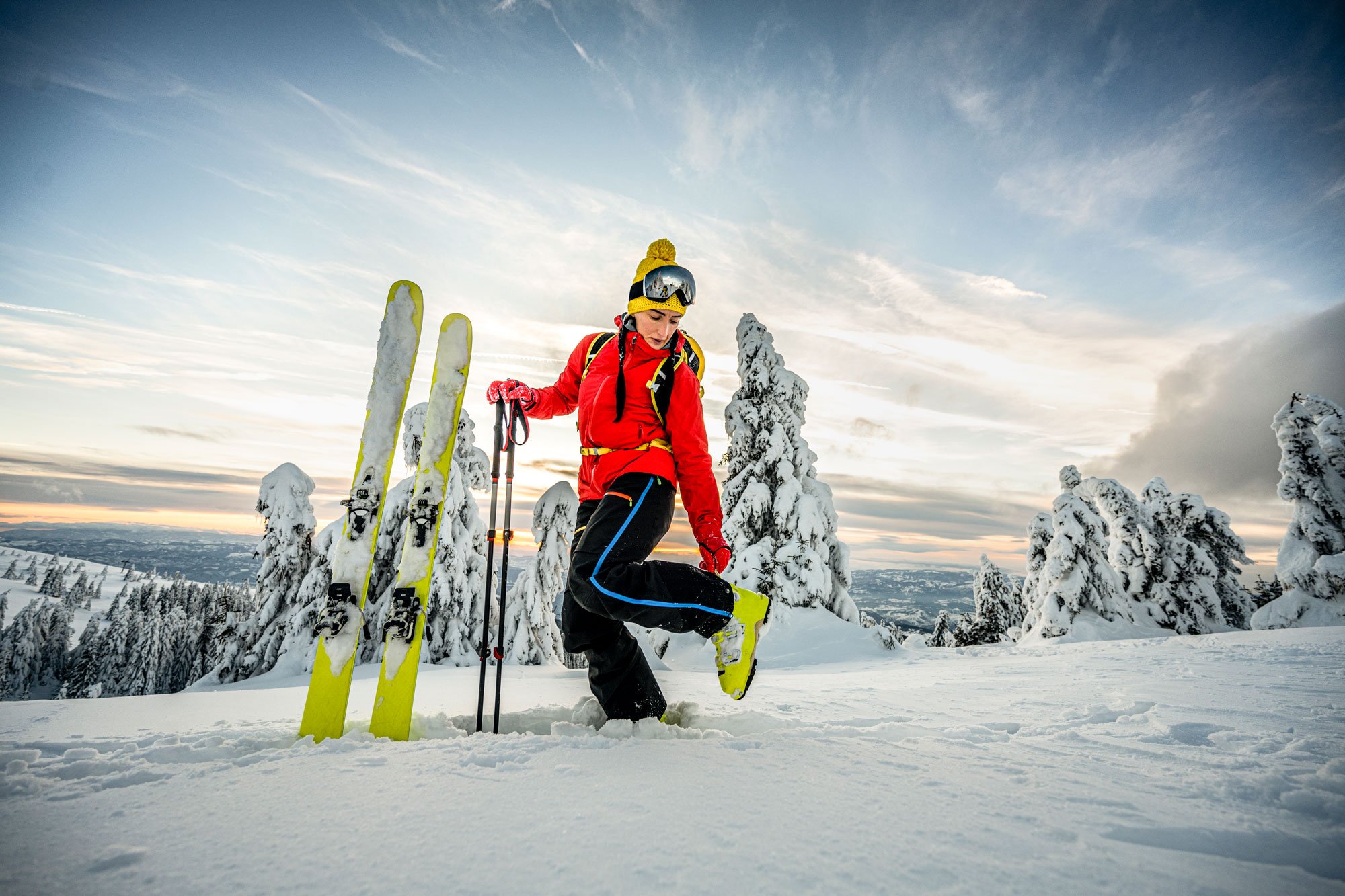 skier wearing yellow ski boots on snowy mountain overlooking sky