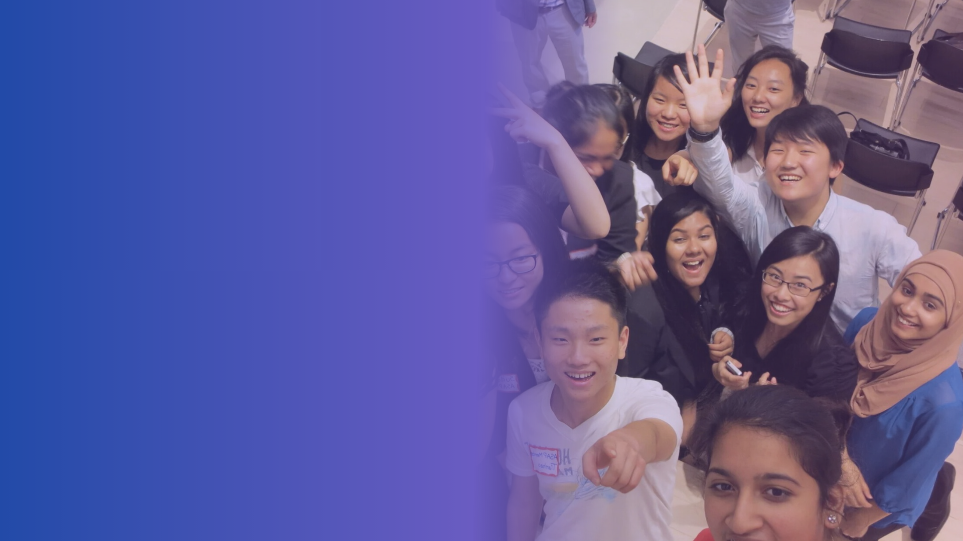 Group of diverse young people smiling and taking a group selfie in an indoor setting.