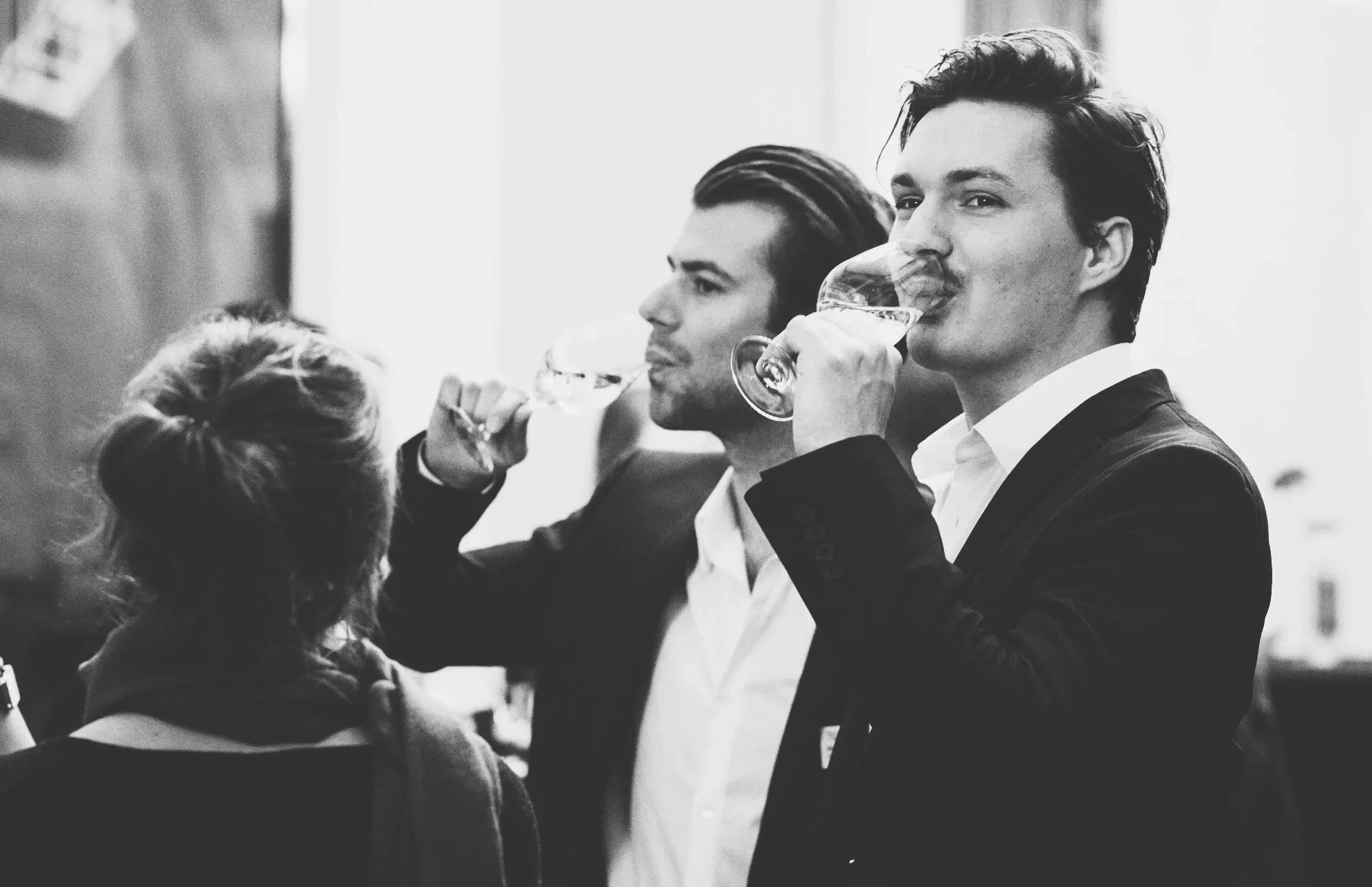 Three people drinking wine at a social gathering.
