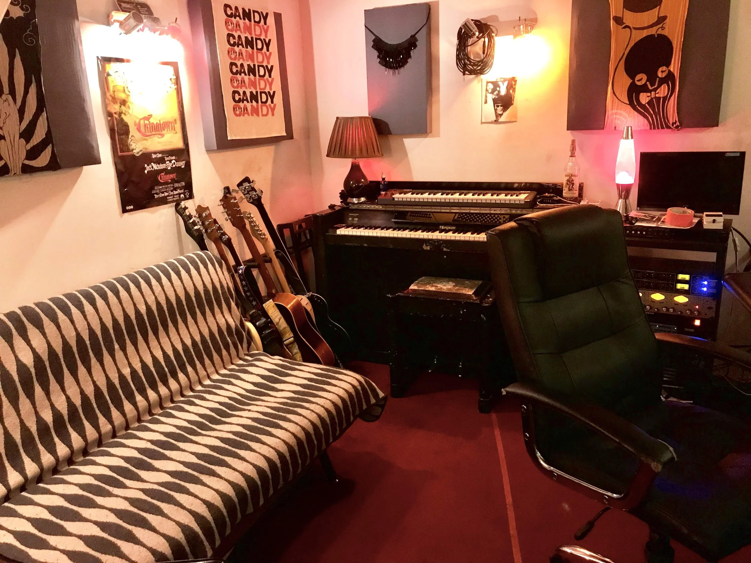 Recording studio control room showing couch, piano and guitars