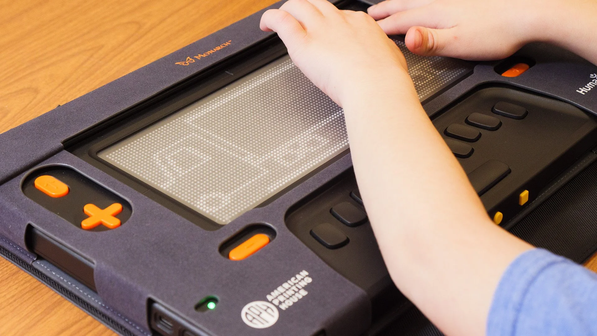 A young person's hand feels a tactile graphic of a truck on a braille display