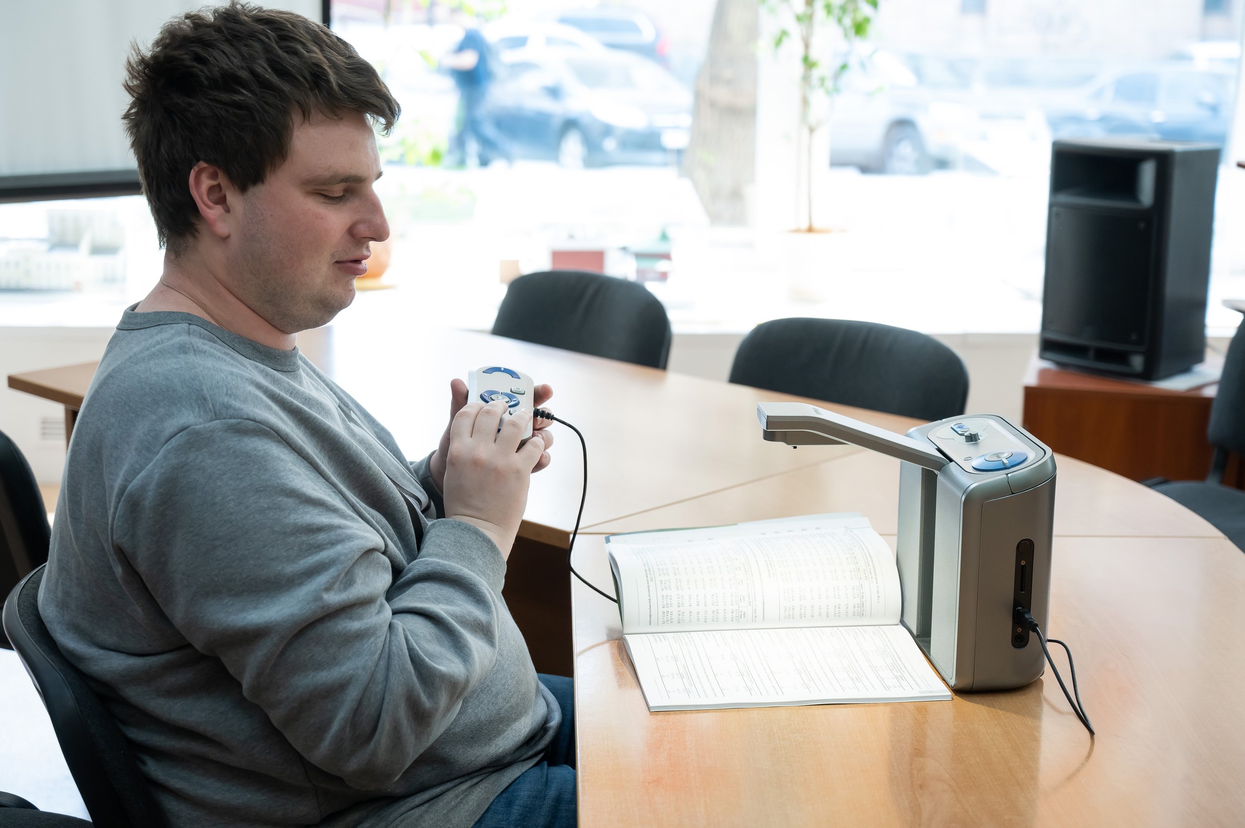 A man sits at a desk reading from a braille device