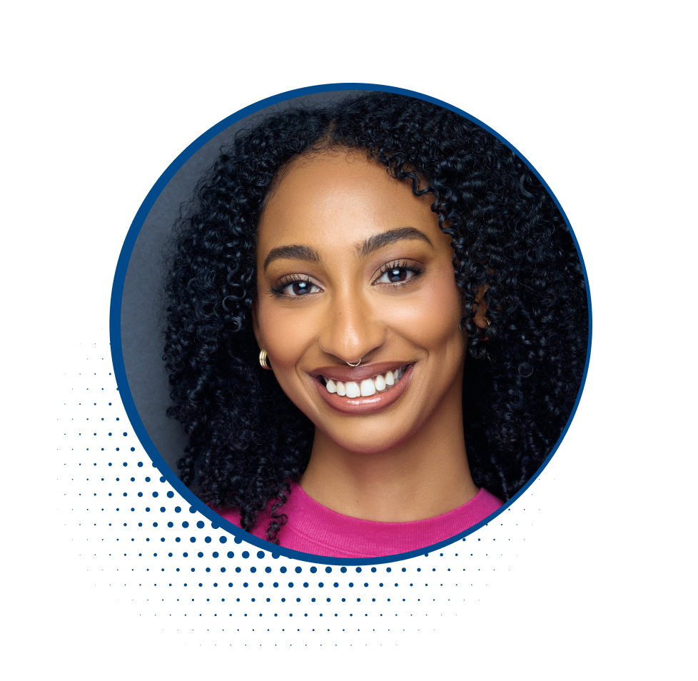 Close-up portrait of a smiling woman with curly black hair, wearing a pink top and gold earrings.