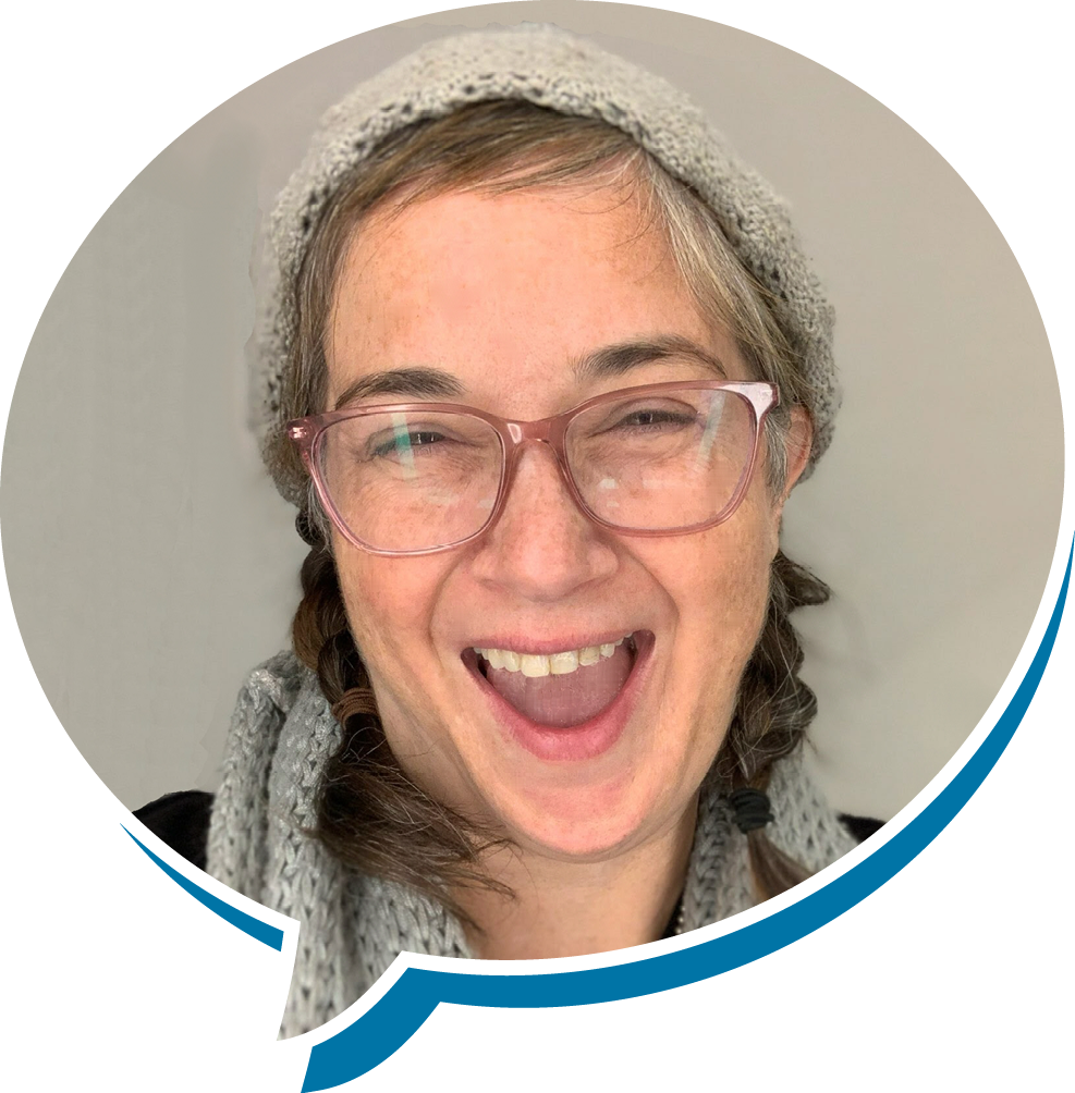 A woman with glasses, a knitted hat, and a scarf, smiling and laughing.