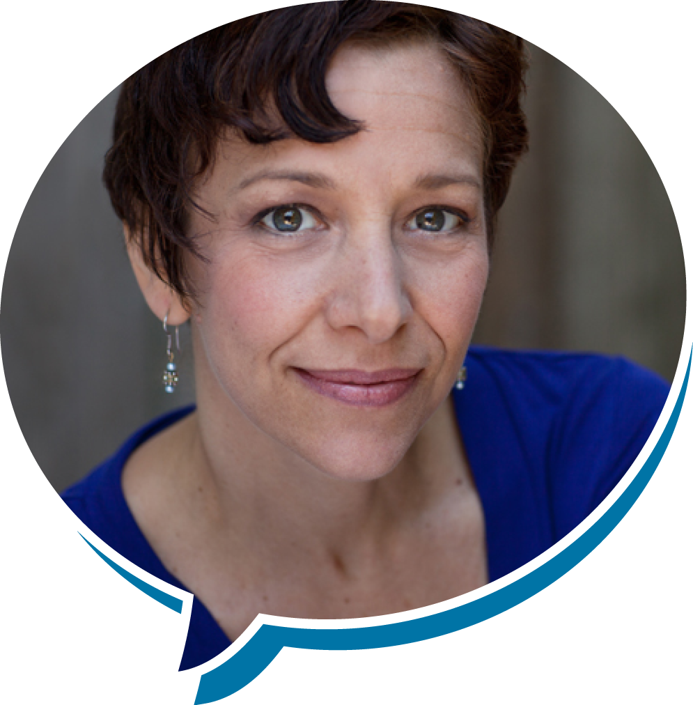 Close-up of a woman with short reddish-brown hair and blue eyes wearing earrings and a blue top, smiling softly.
