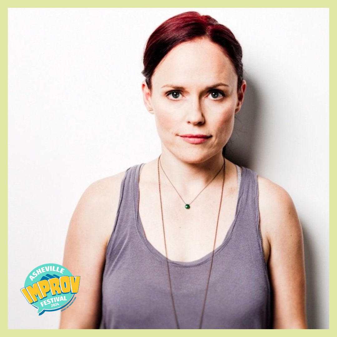 Portrait of a woman with short red hair wearing a purple tank top and a necklace standing against a white wall. The Asheville Improv Festival 2024 logo is in the bottom left corner.