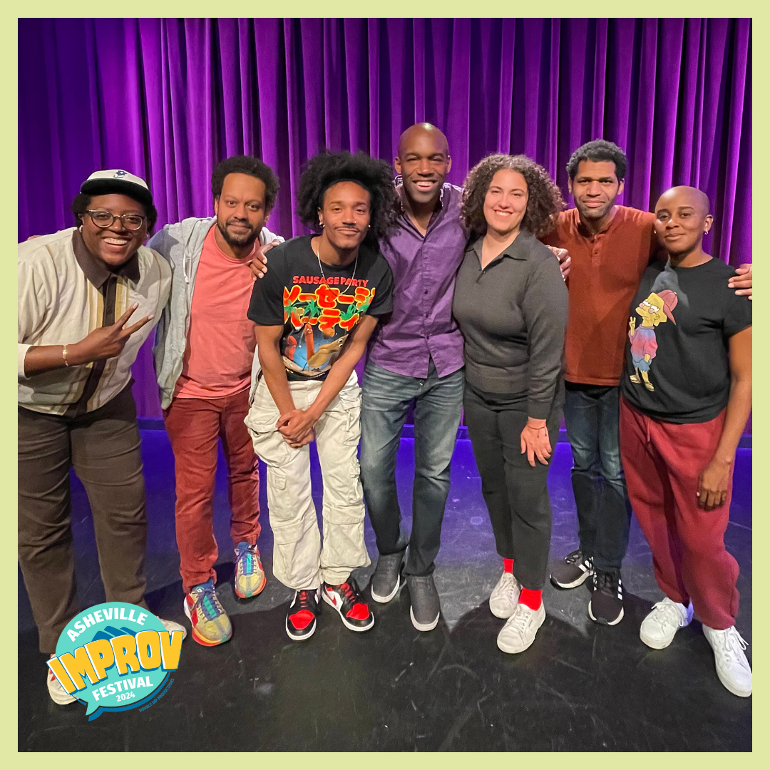 A group of seven diverse comedians posing on stage at the Asheville Improv Festival 2024, with purple curtains in the background and a festival logo in the corner.