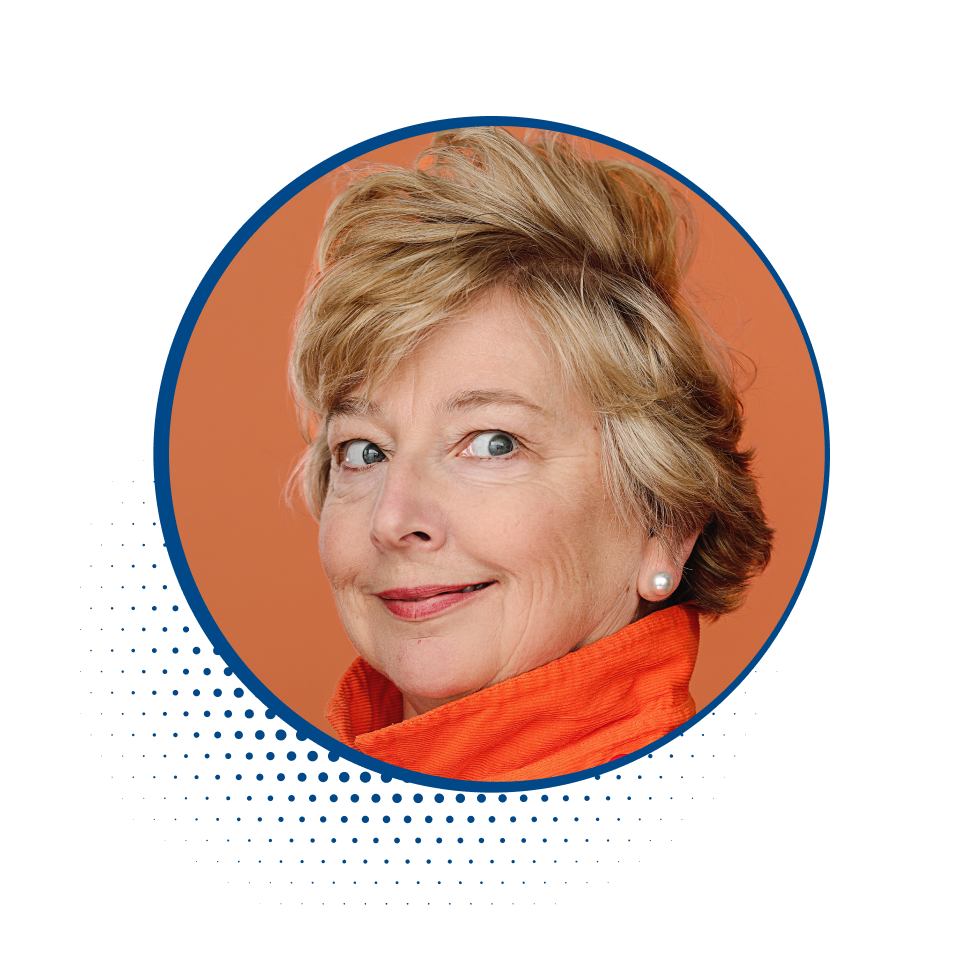 Close-up portrait of an older woman with short blonde hair, wearing a red-orange scarf and pearl earrings, smiling against a peach background.