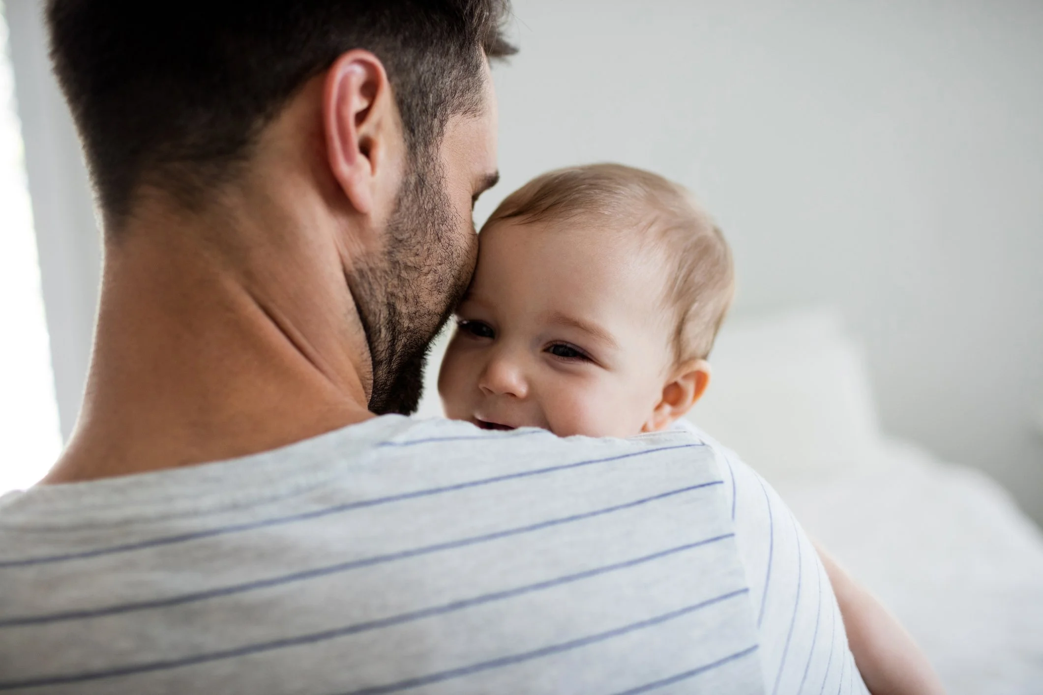Close-up of a man holding a smiling baby close to his face indoors.