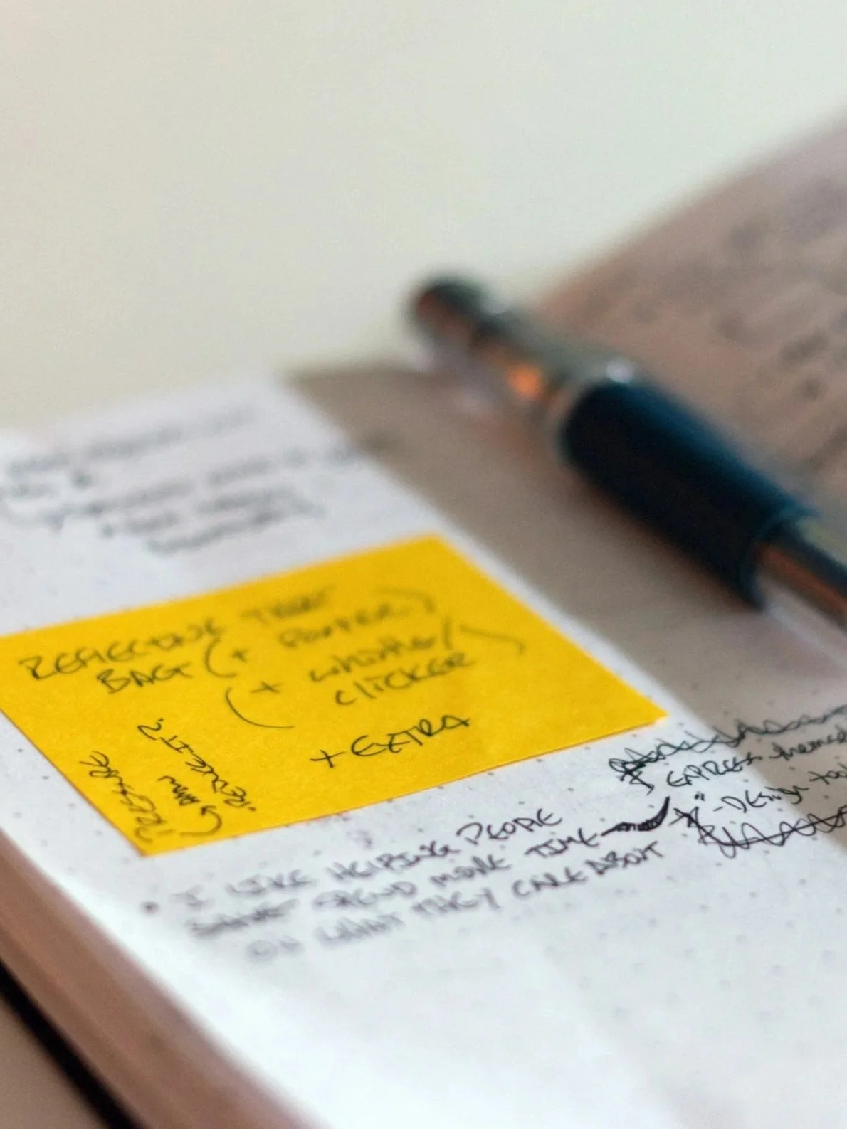 Close-up of a yellow sticky note with handwritten notes and a black ballpoint pen on paper.