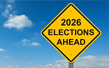Yellow road sign reading "2026 Elections Ahead" set against a cloudy blue sky.