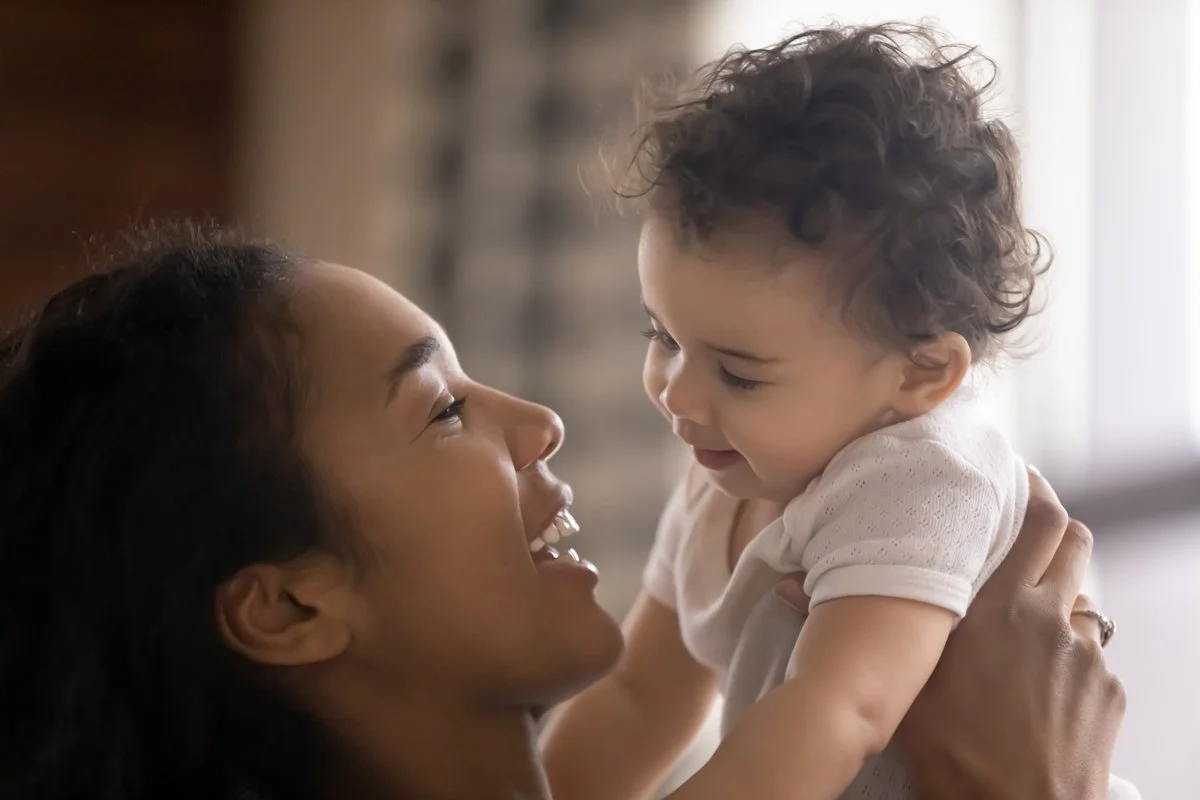 Closeup of mother and baby smiling at eachother.