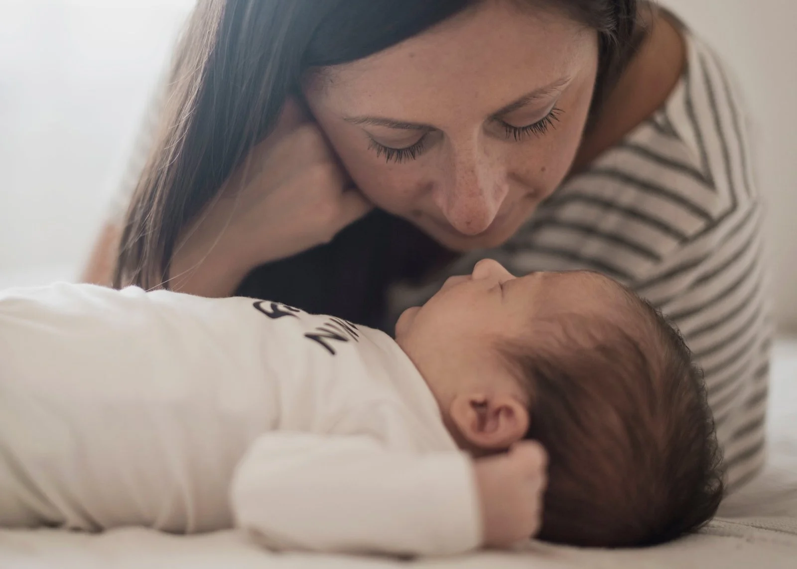 Closeup of a mother looking at her sleeping baby.