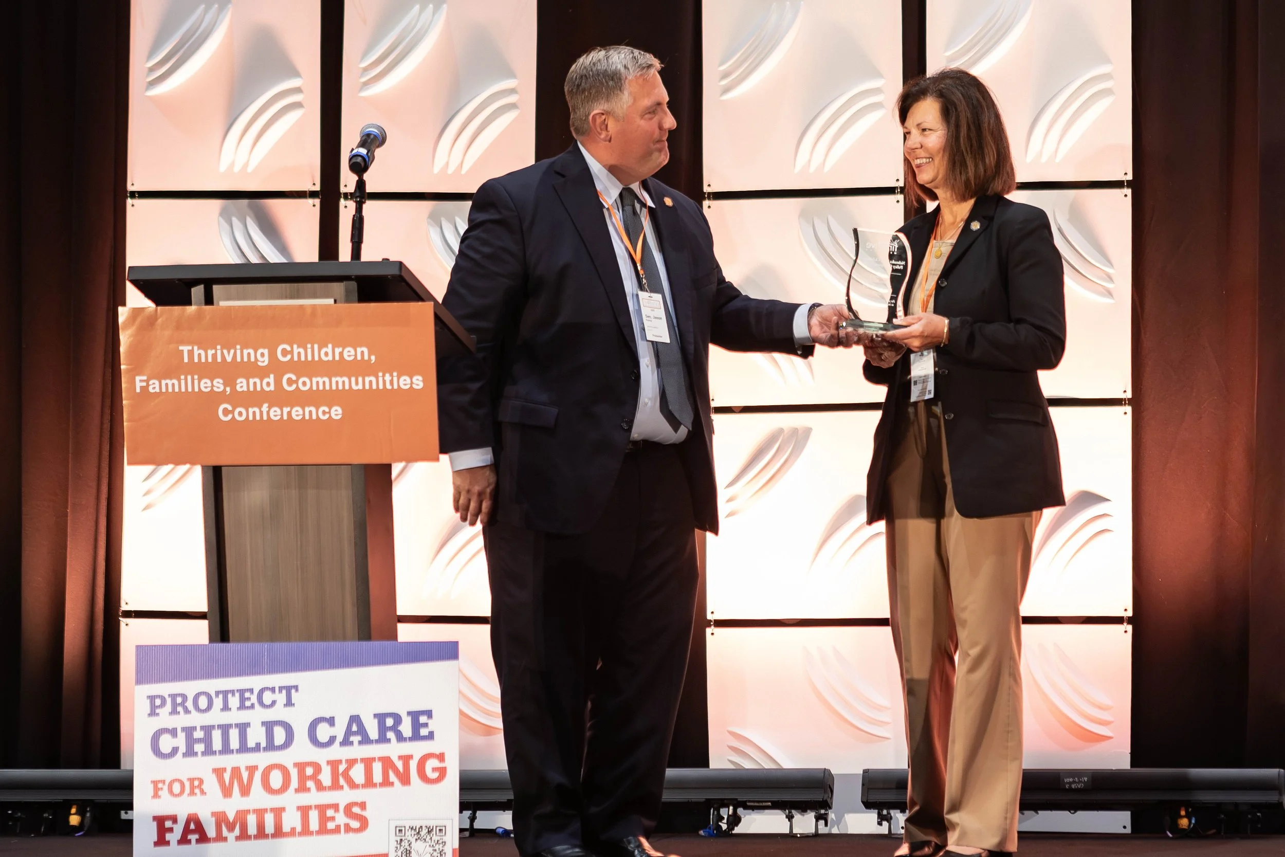 Photo of Senator Prokop handing award to Senator Ibach on stage.