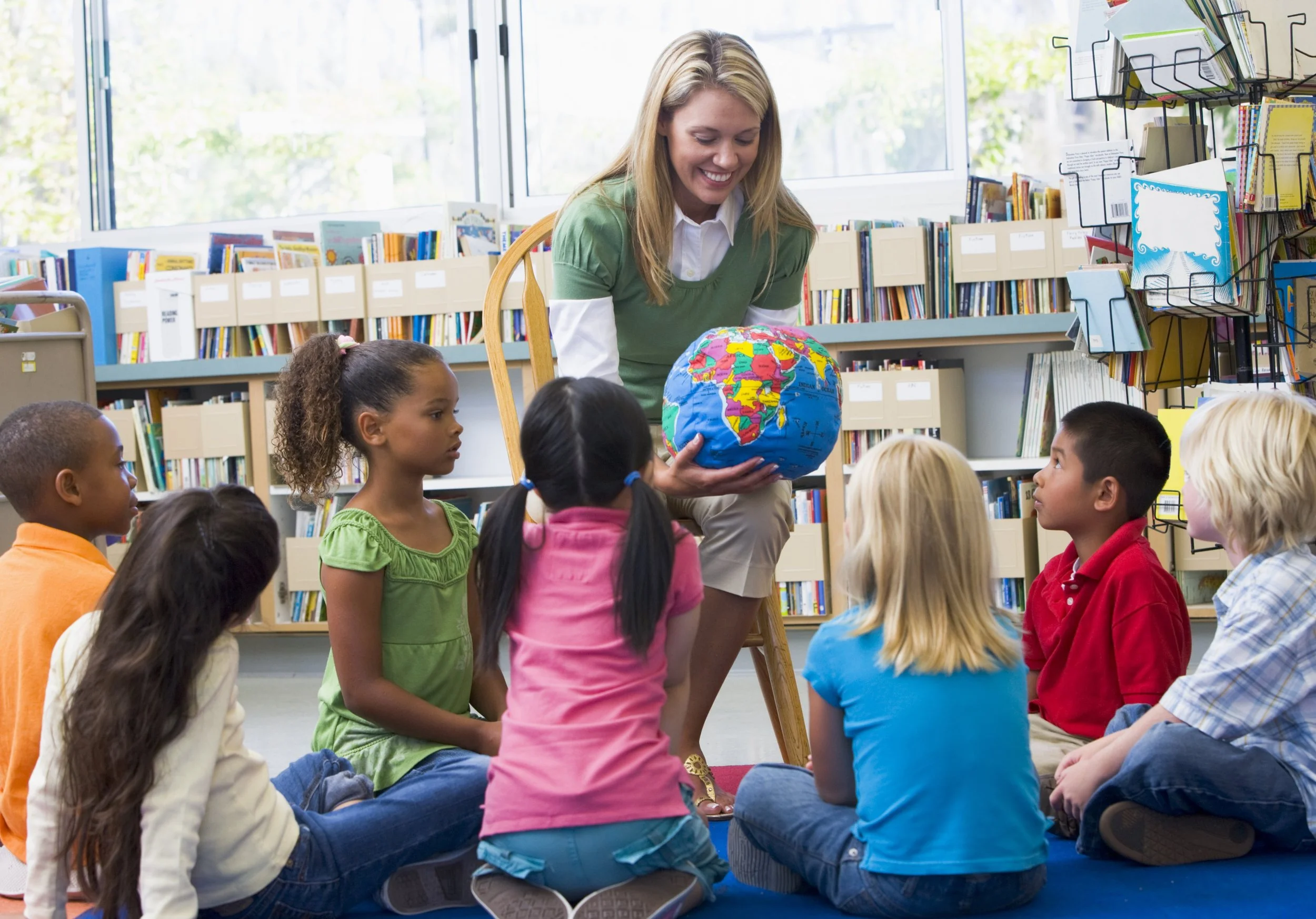 Teacher in a class, showing students a globe
