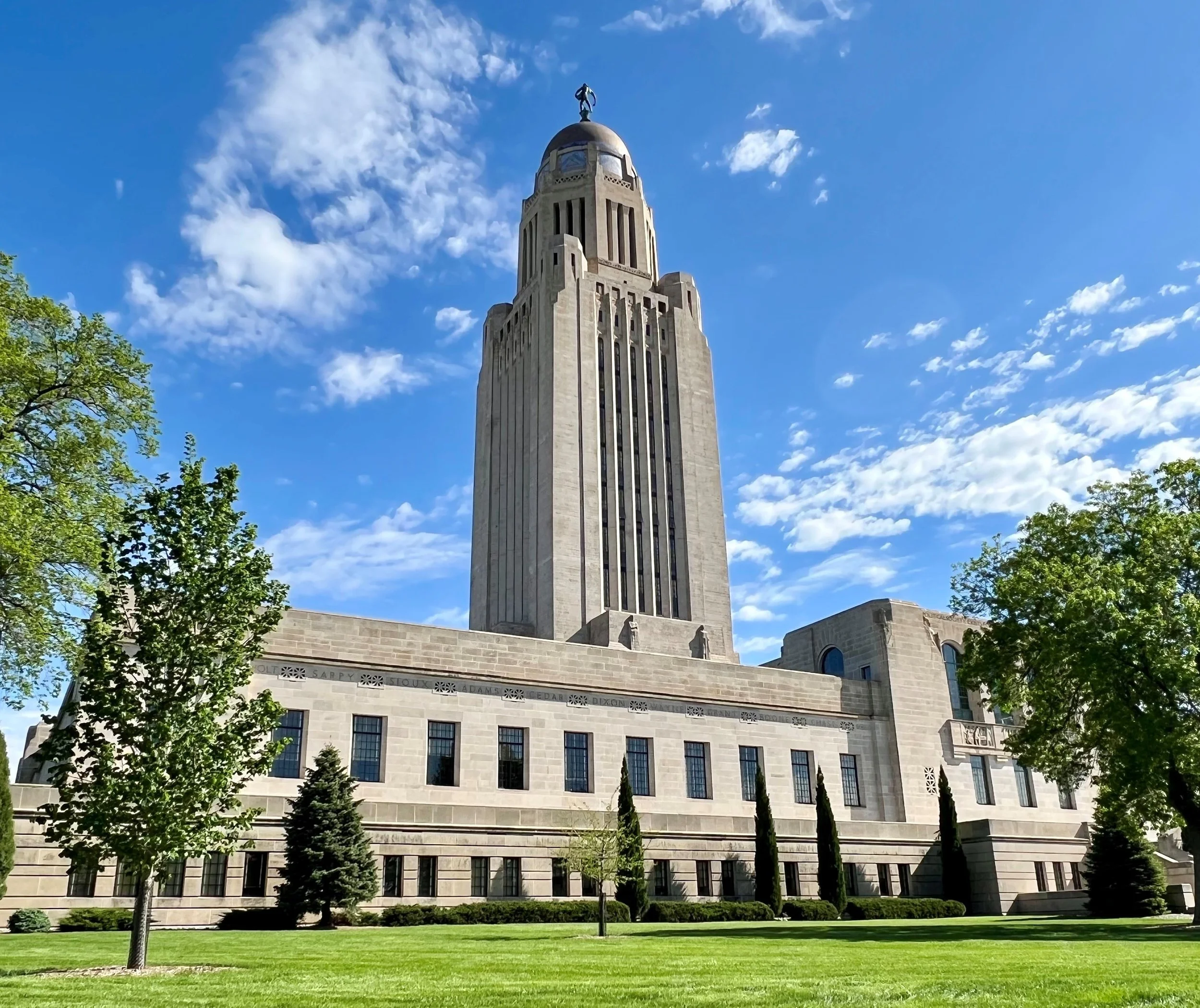 View of the Nebraska Capitol building against a blue sky with white clouds