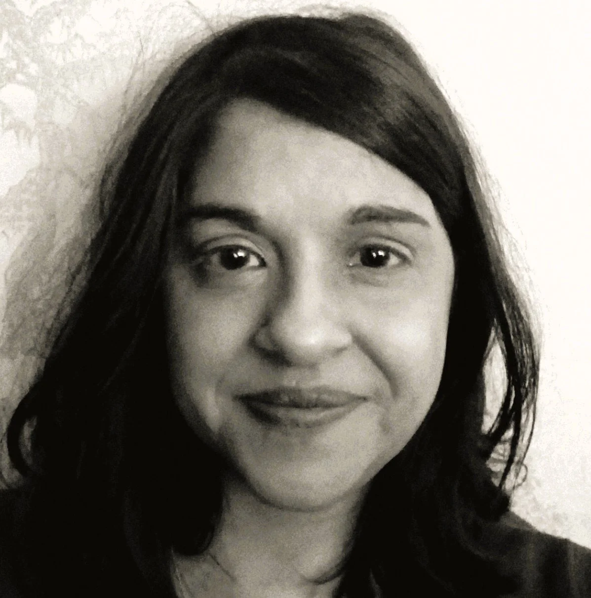 Close-up black-and-white photo of the author. Dark hair, smiling softly in front of a light wall.