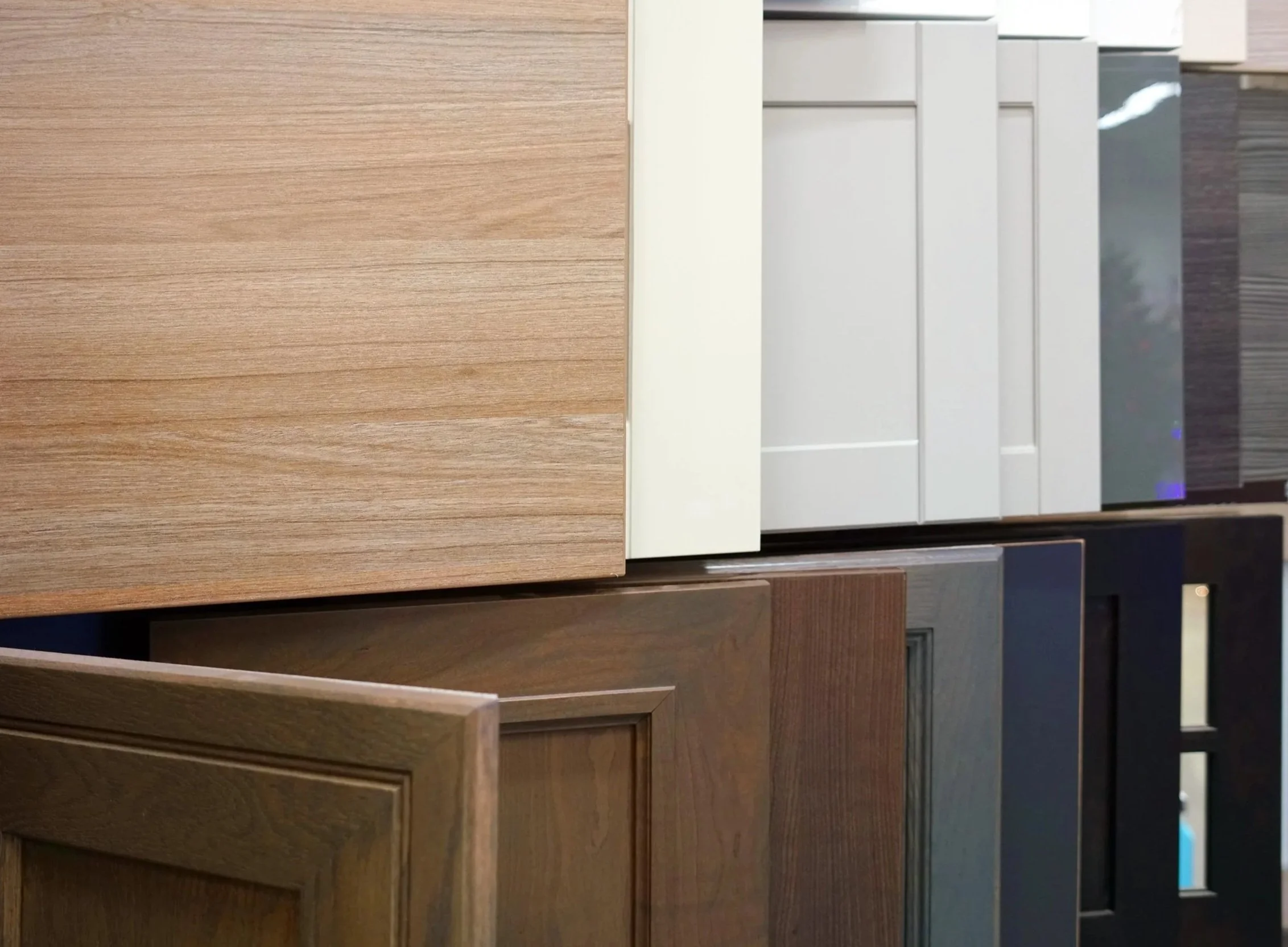 Display of various cabinet doors in different wood finishes and colors.