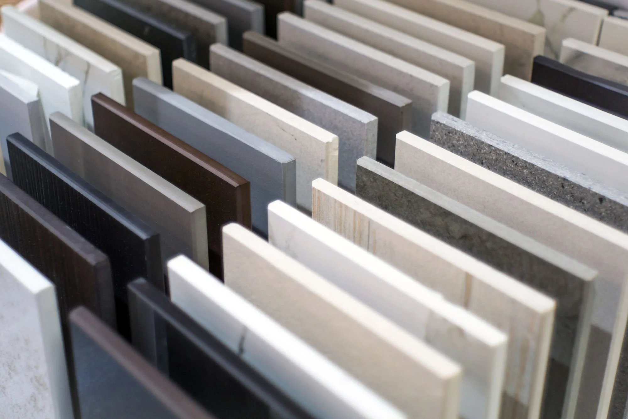 Multiple samples of different types and colors of tile slabs arranged vertically in a display.