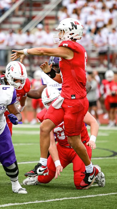 Football player in red uniform jumping over a player on the ground during a game