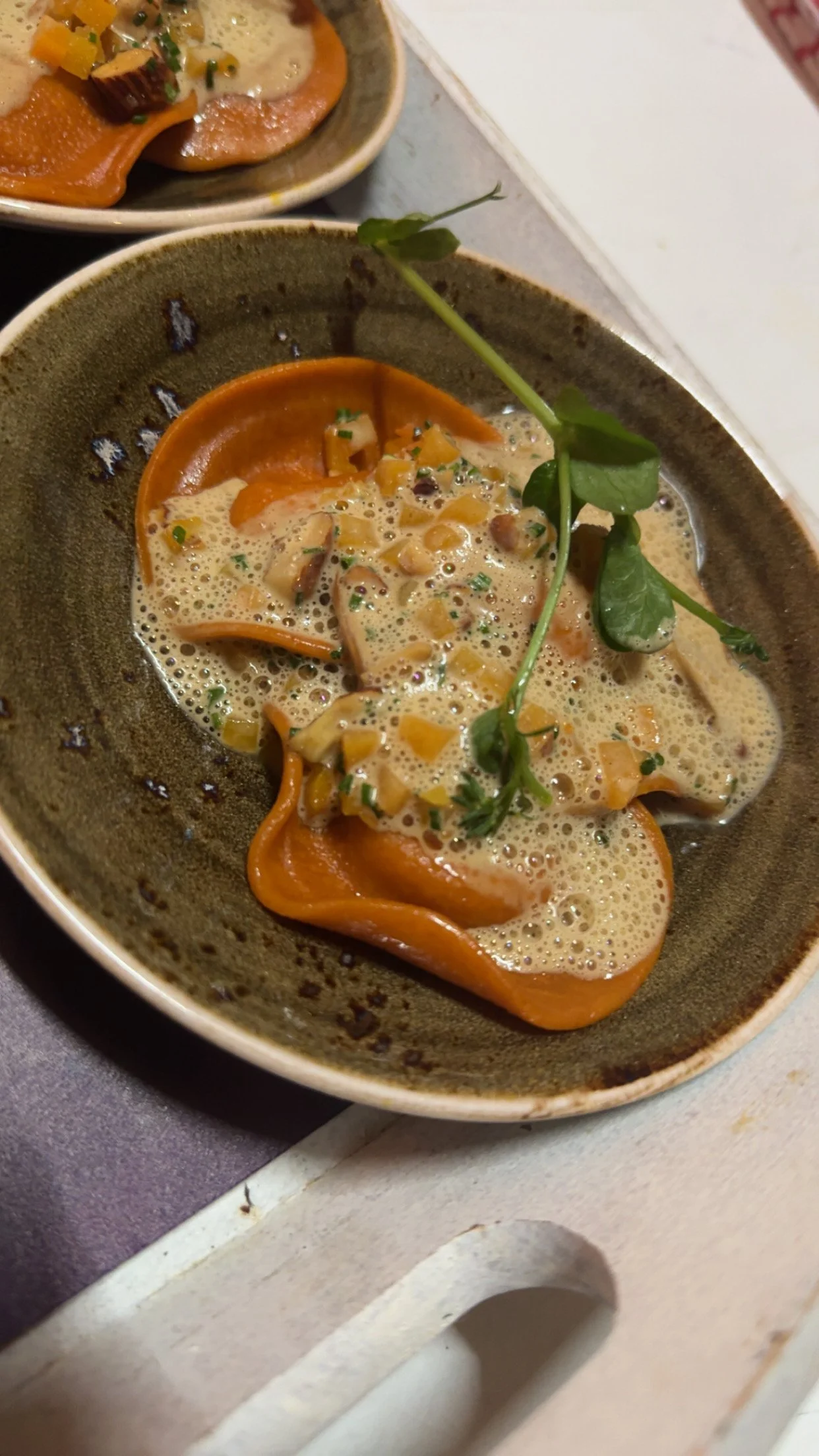 Dish with sliced salmon in a creamy sauce, garnished with herbs and accompanied by a sprig of microgreens.