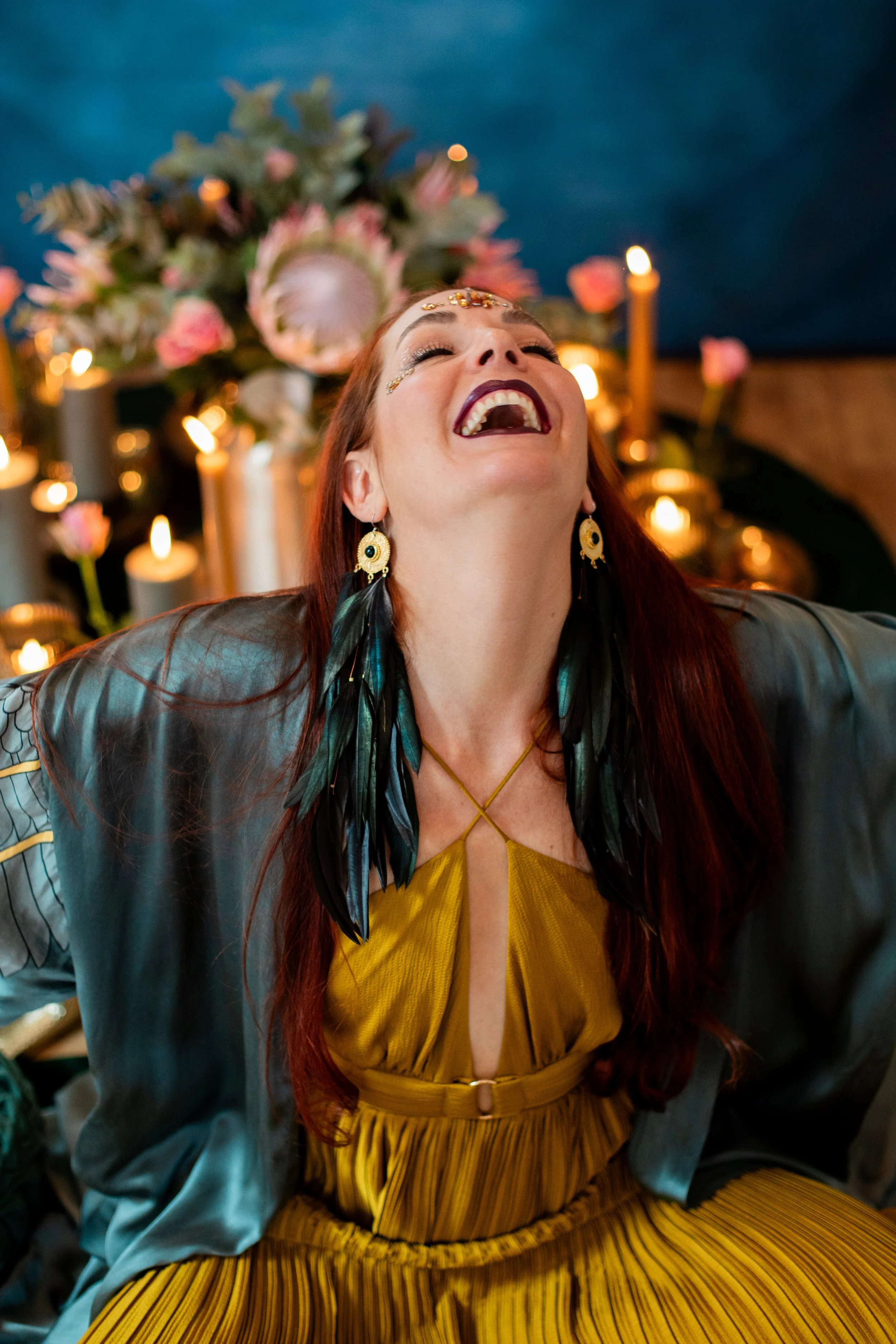 Woman in black swimsuit holding a pineapple above water at the beach, with water splashing and a clear blue sky in the background.