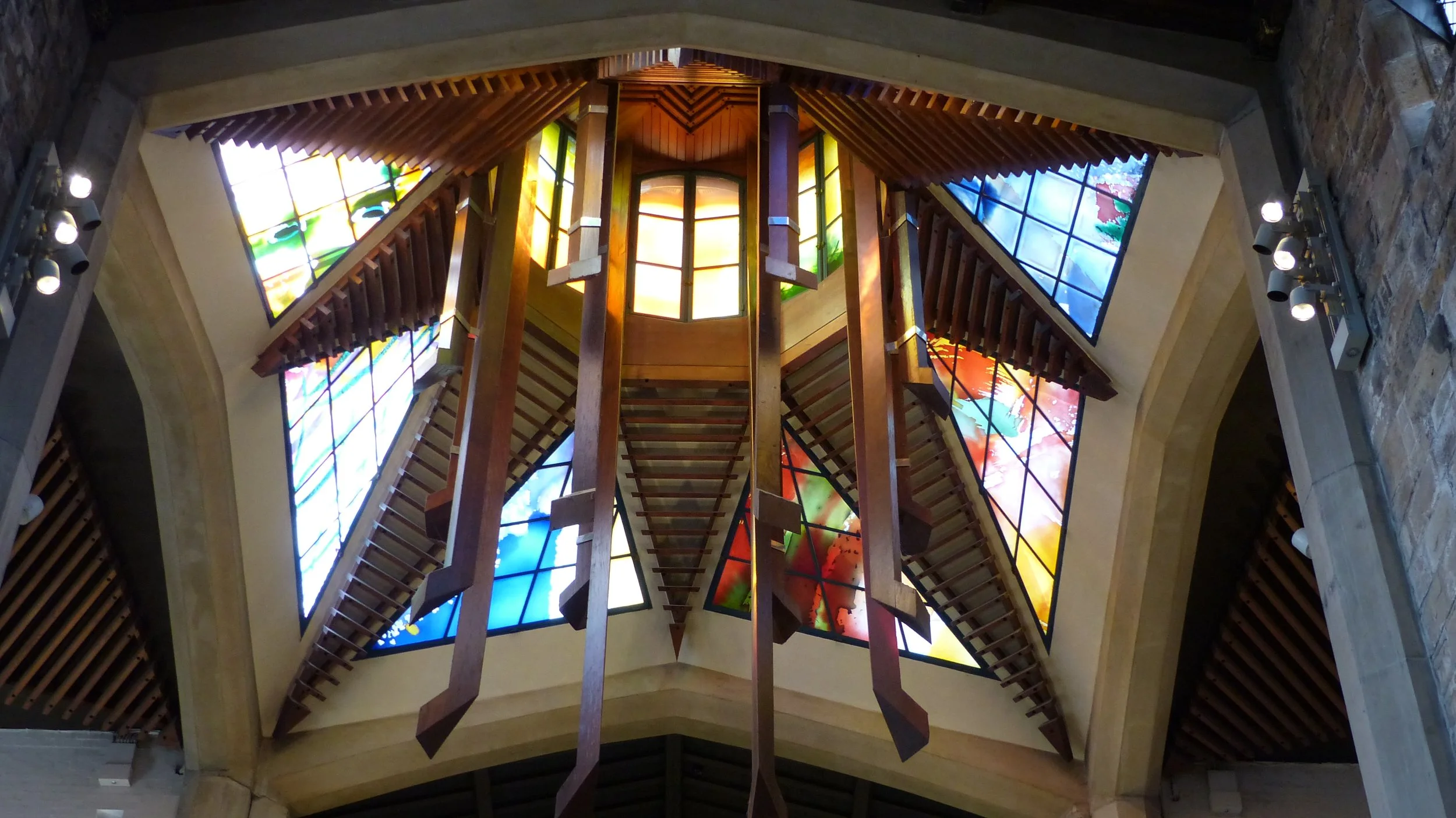 Interior view of a ceiling with a wooden staircase and colorful stained glass windows