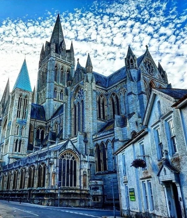 A large Gothic-style cathedral with tall spires and pointed arches, built with stone, set against a partly cloudy sky.