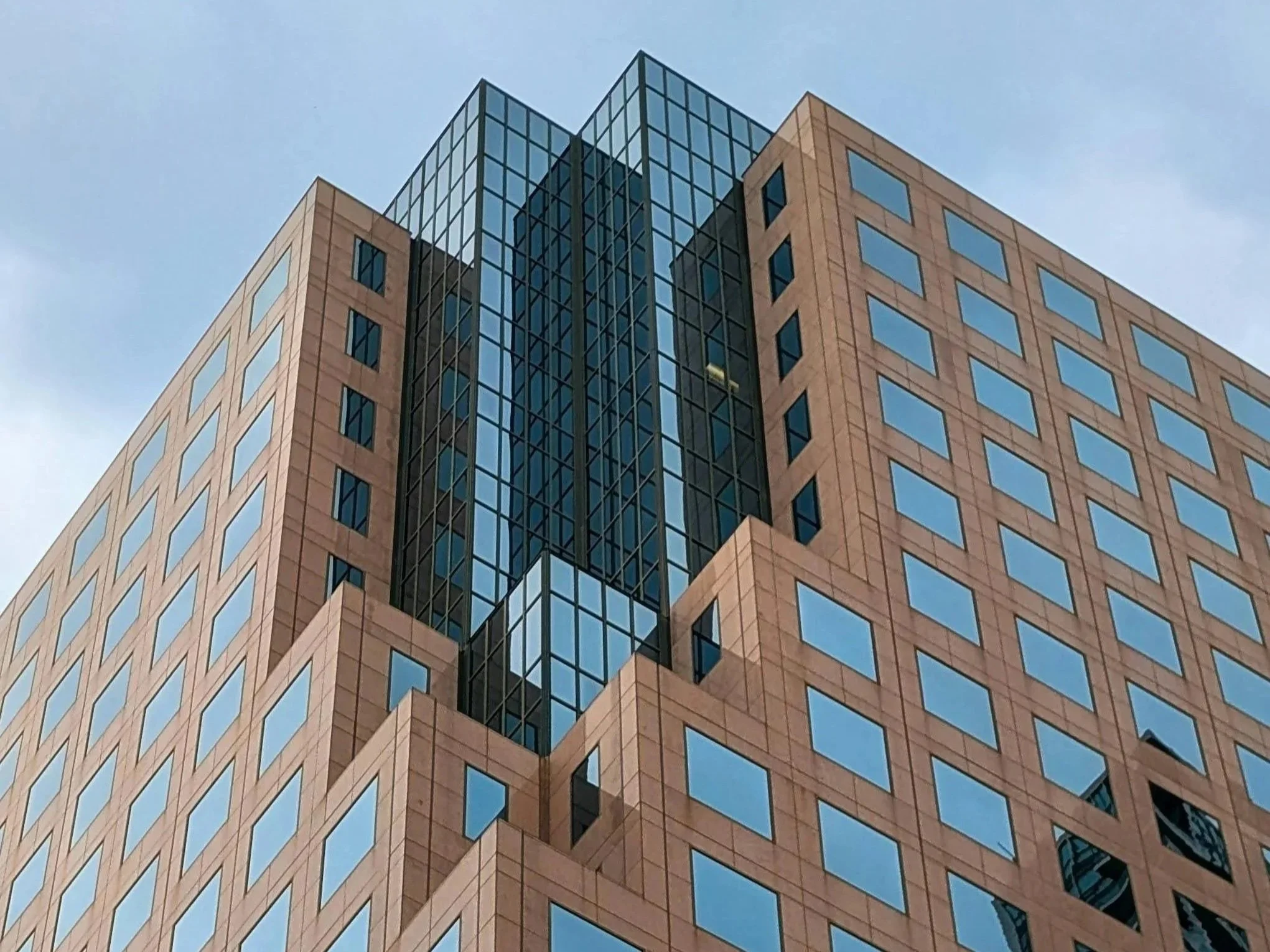Close-up of a modern high-rise building with tan brick facade and numerous glass windows.