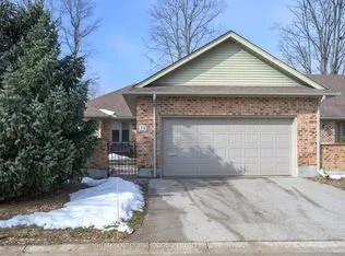 Front view of a house with a brick and siding exterior, a gray garage door, and a driveway, with snow on the ground.