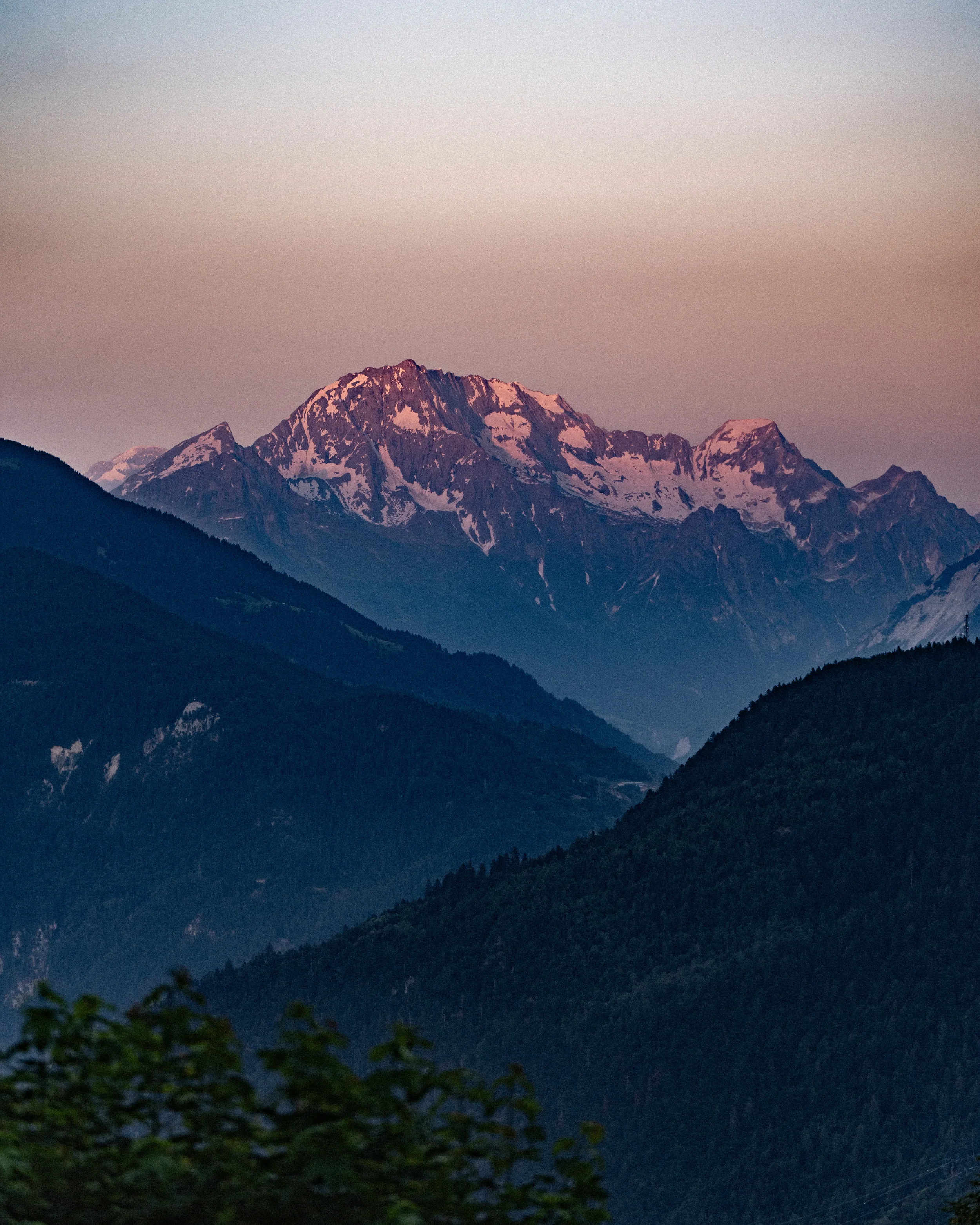 Montagnes avec sommet enneigé au coucher du soleil, en arrière-plan un ciel pastel