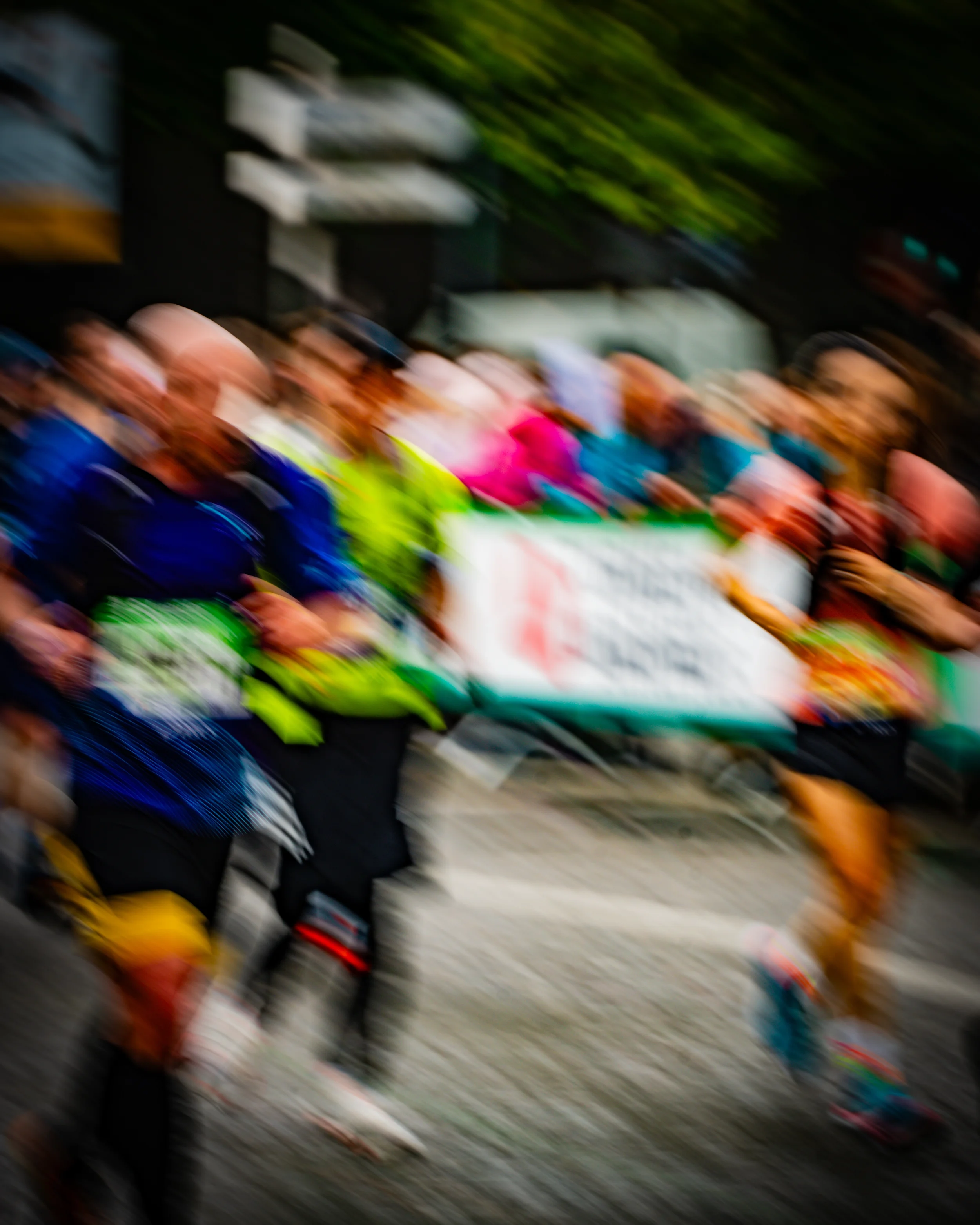 Groupe de personnes participant à une marche ou une manifestation, portant une banderole et des vêtements colorés.