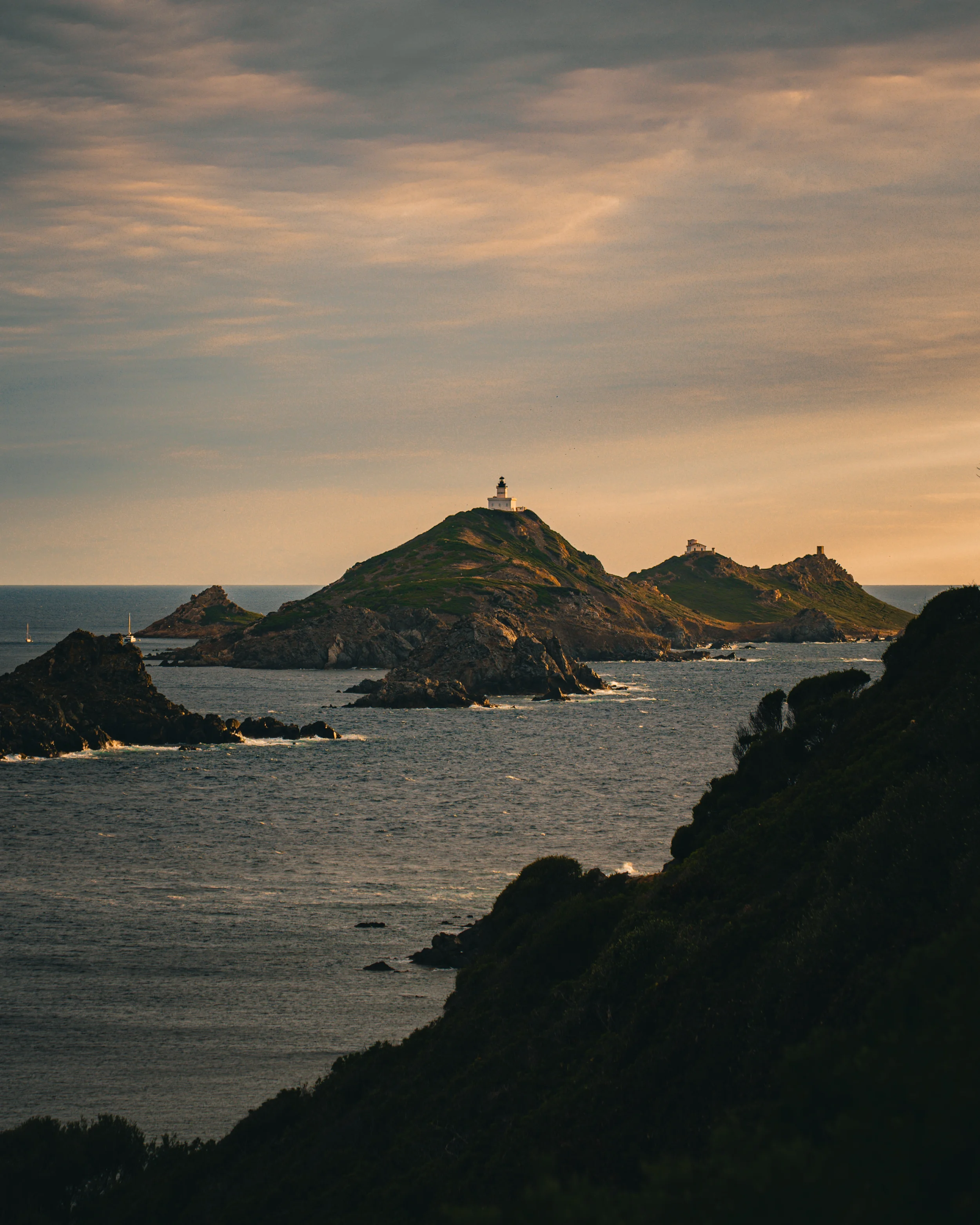 Paysage marin avec des îles rocheuses et des phares au coucher de soleil.