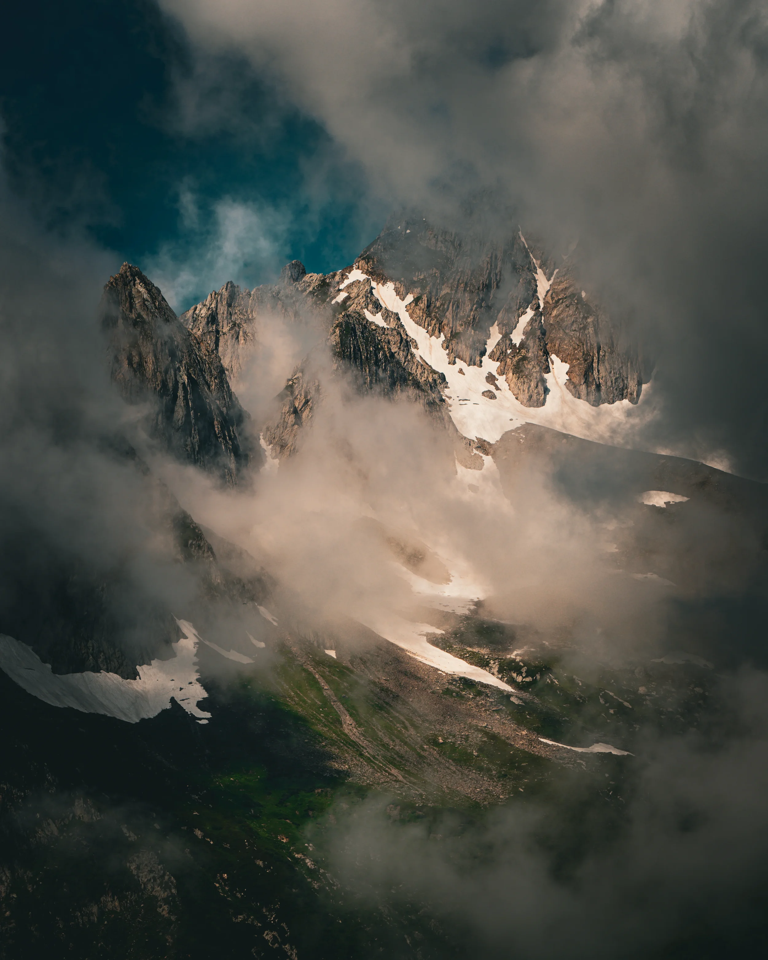 Montagne enneigée en partie cachée par des nuages, avec un ciel nuageux en arrière-plan.
