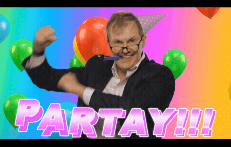 A man in a suit holding a pen in his mouth, surrounded by colorful balloons, with the word 'PARTAY!!!' in bold pink letters