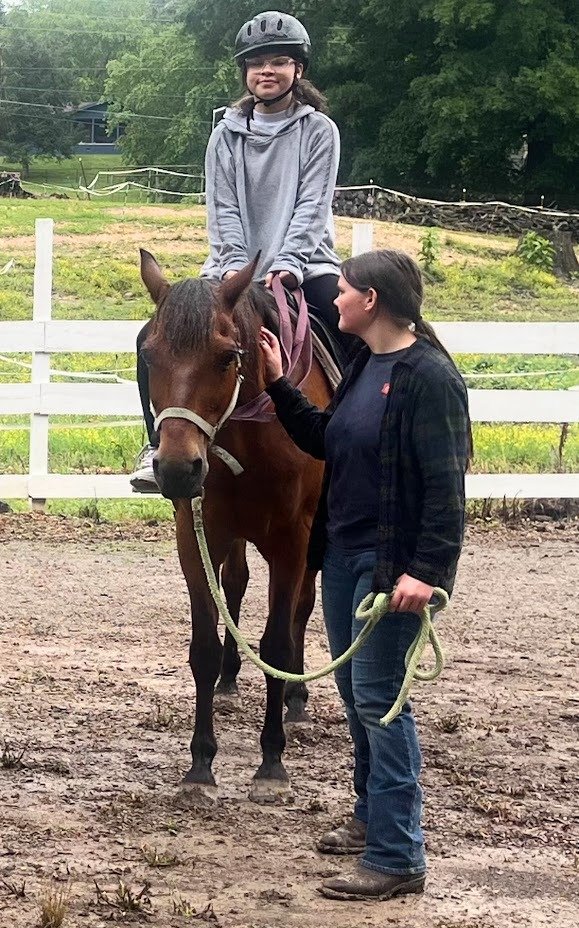 Health blog - young girl sitting on a horse for therapeutic riding session