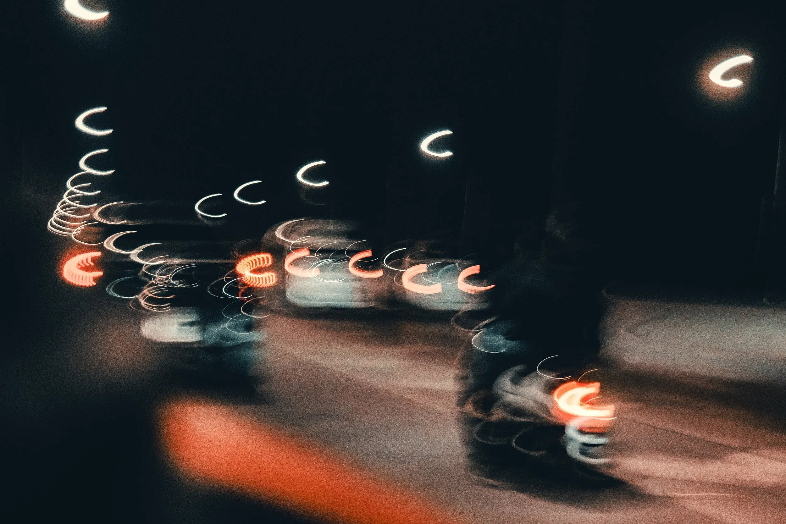 Blurred view of a city street at night with streetlights and vehicle taillights creating bokeh effects.