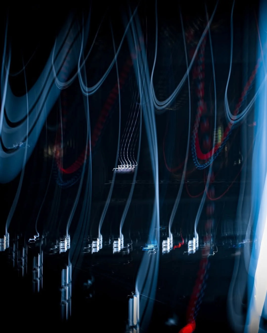 Light trails creating abstract lines on a dark background, resembling long-exposure photography of moving lights.