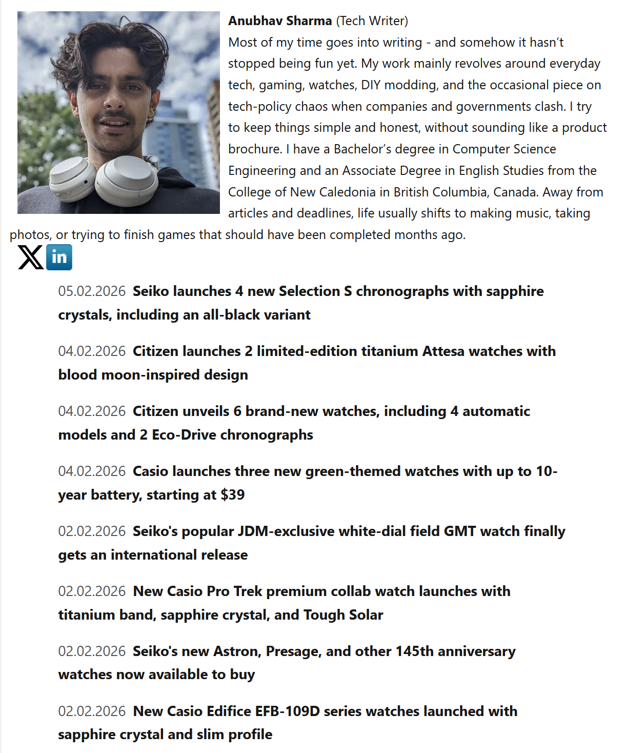 A man with dark, wavy hair and a slight beard, wearing a black shirt and white over-ear headphones around his neck, standing outdoors with a cityscape background. The sky is partly cloudy.