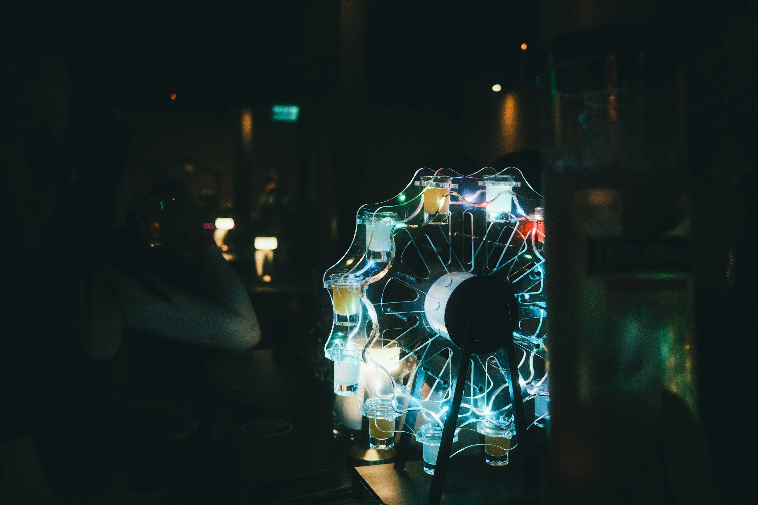 A colorful, illuminated Tesla coil quivering in a dark room, emitting sparks and light.