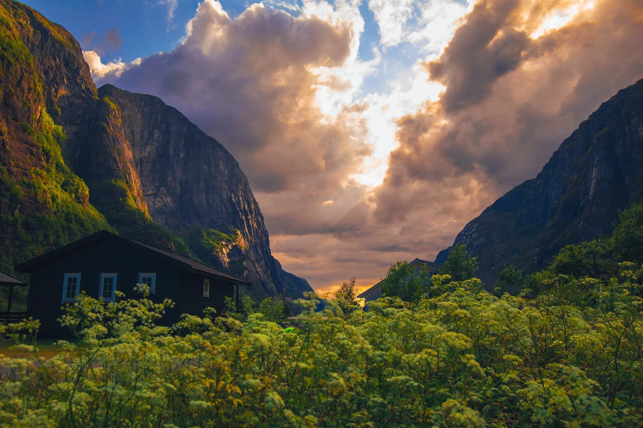 Light breaking through clouds over a valley in Norway with partial illumination on mountains and foreground